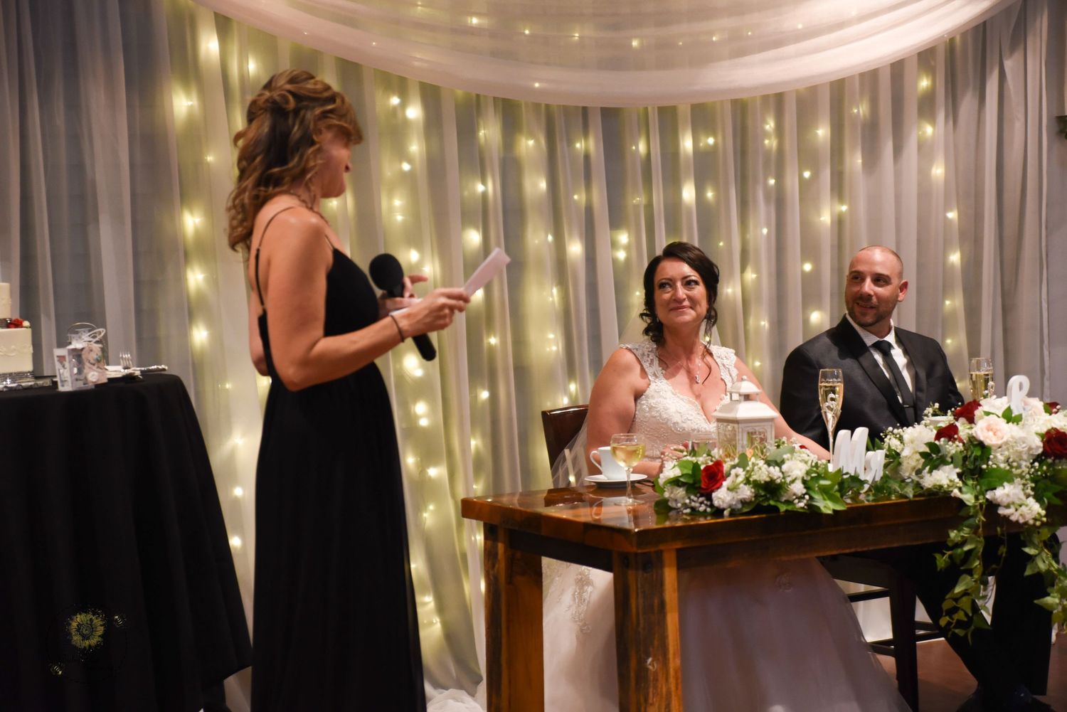 Wedding reception room decorated with white draping and string lights creating romantic ambiance.