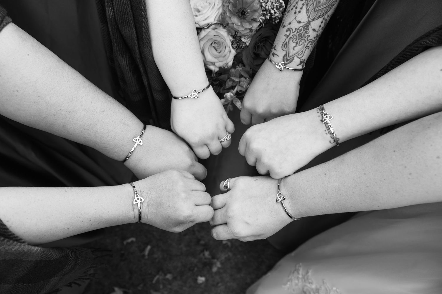 Close-up black and white photo of hands exchanging rings during wedding ceremony.