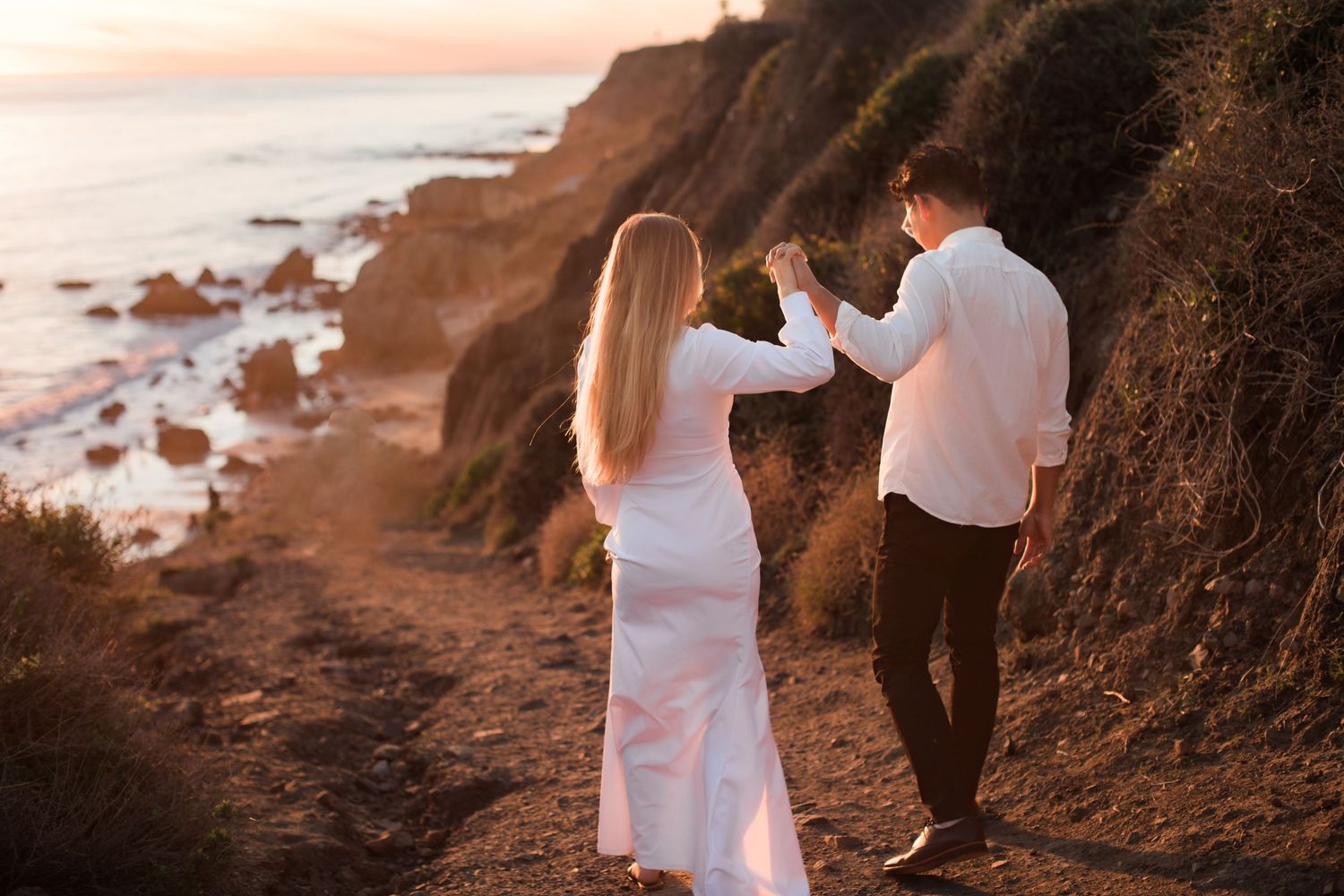 A couple sharing a special moment on a coastal trail during golden hour.