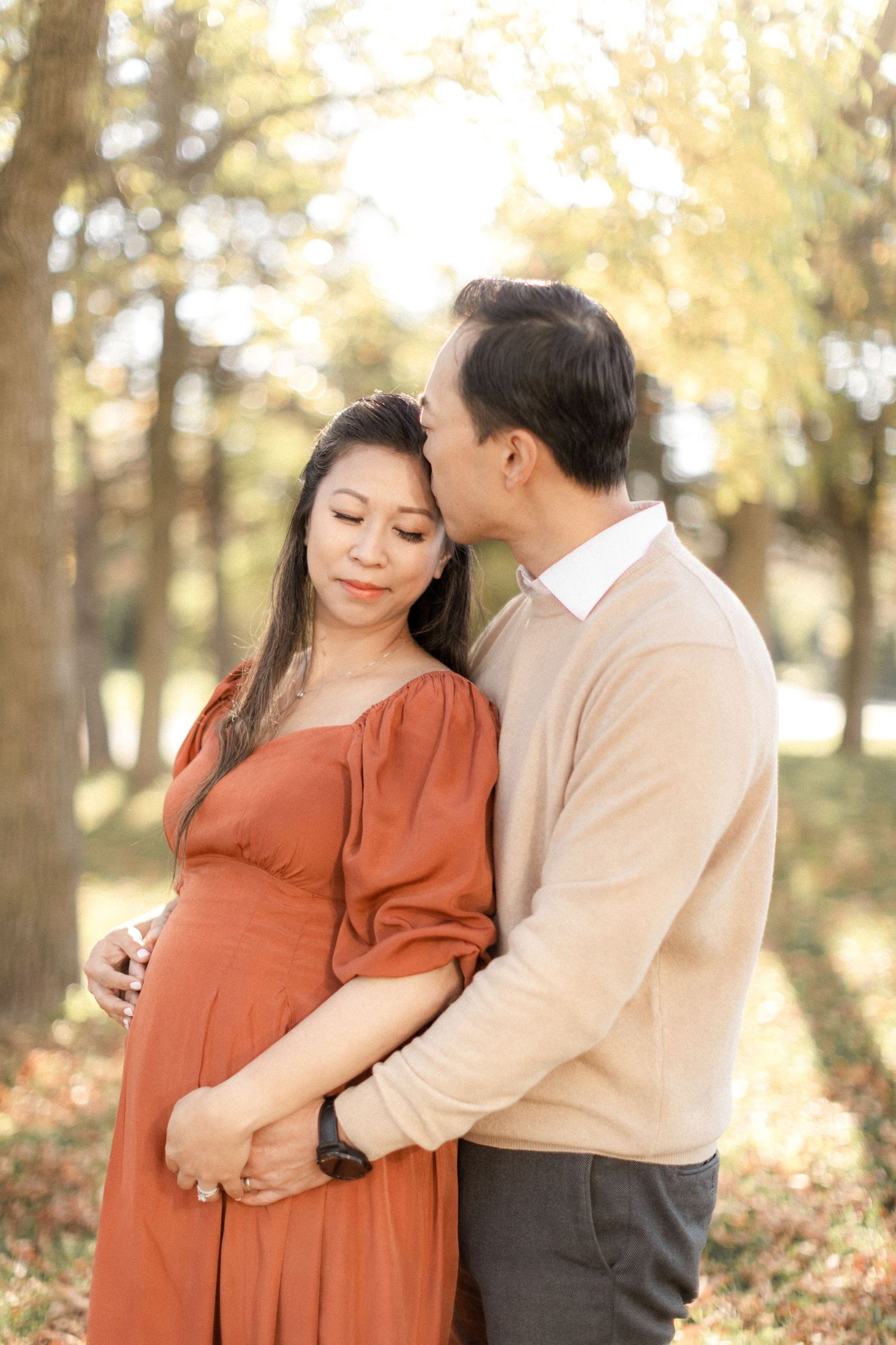 Tender autumn maternity portrait with couple in coordinated earth-toned outfits.