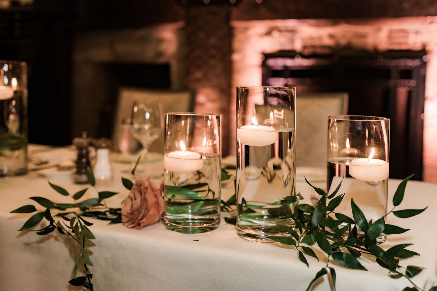 Wedding table decor featuring floating candles and greenery garlands.