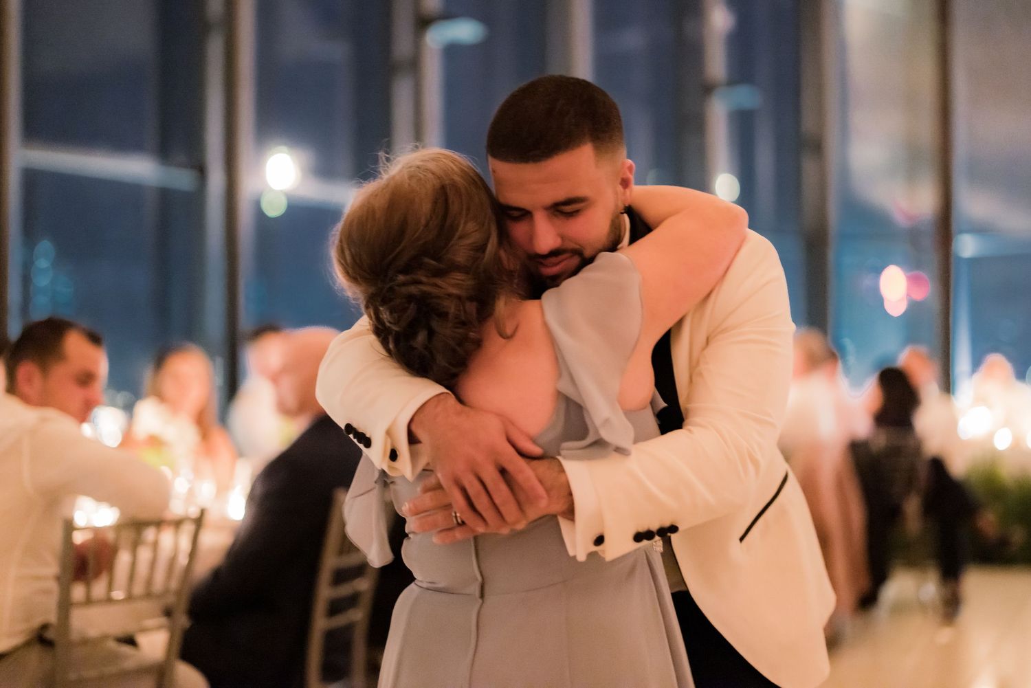A tender embrace on the dance floor during a wedding reception in an illuminated modern venue.