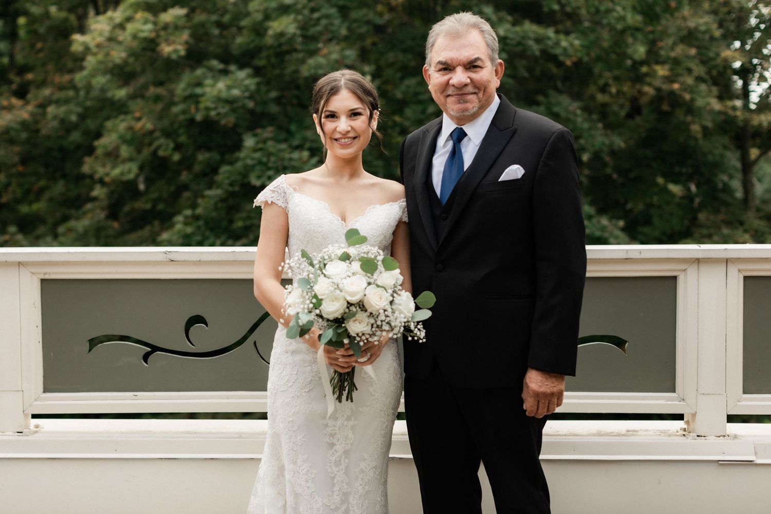 A wedding portrait taken outdoors on a white balcony railing.