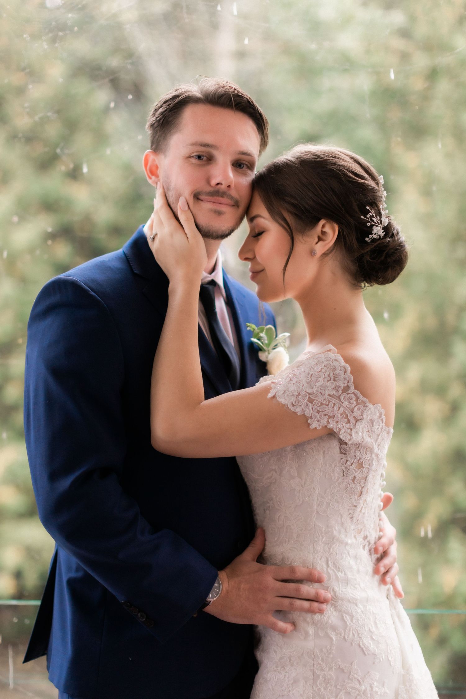 Intimate wedding portrait captured in soft natural light with forest backdrop.