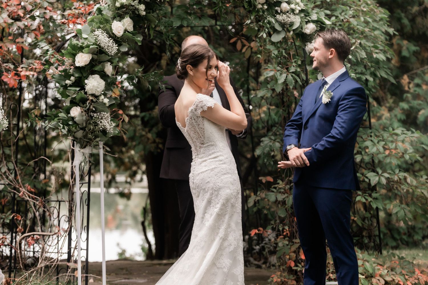 Emotional wedding moment in garden setting with couple sharing first look near blooming roses.