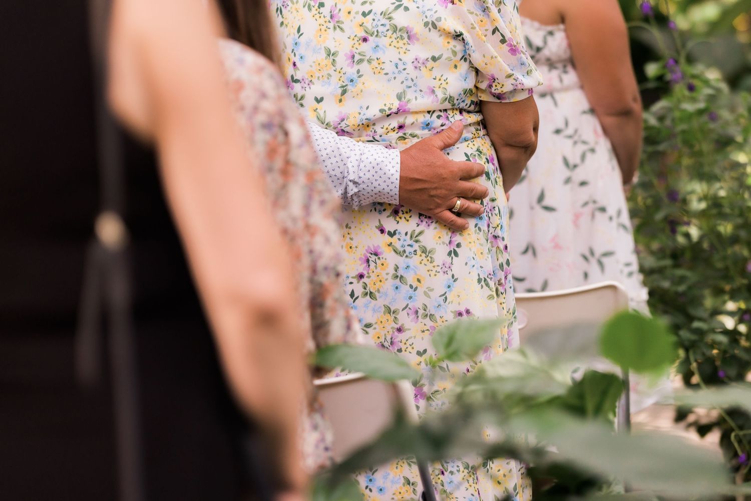 Detail shot of hands holding during an outdoor garden wedding ceremony.
