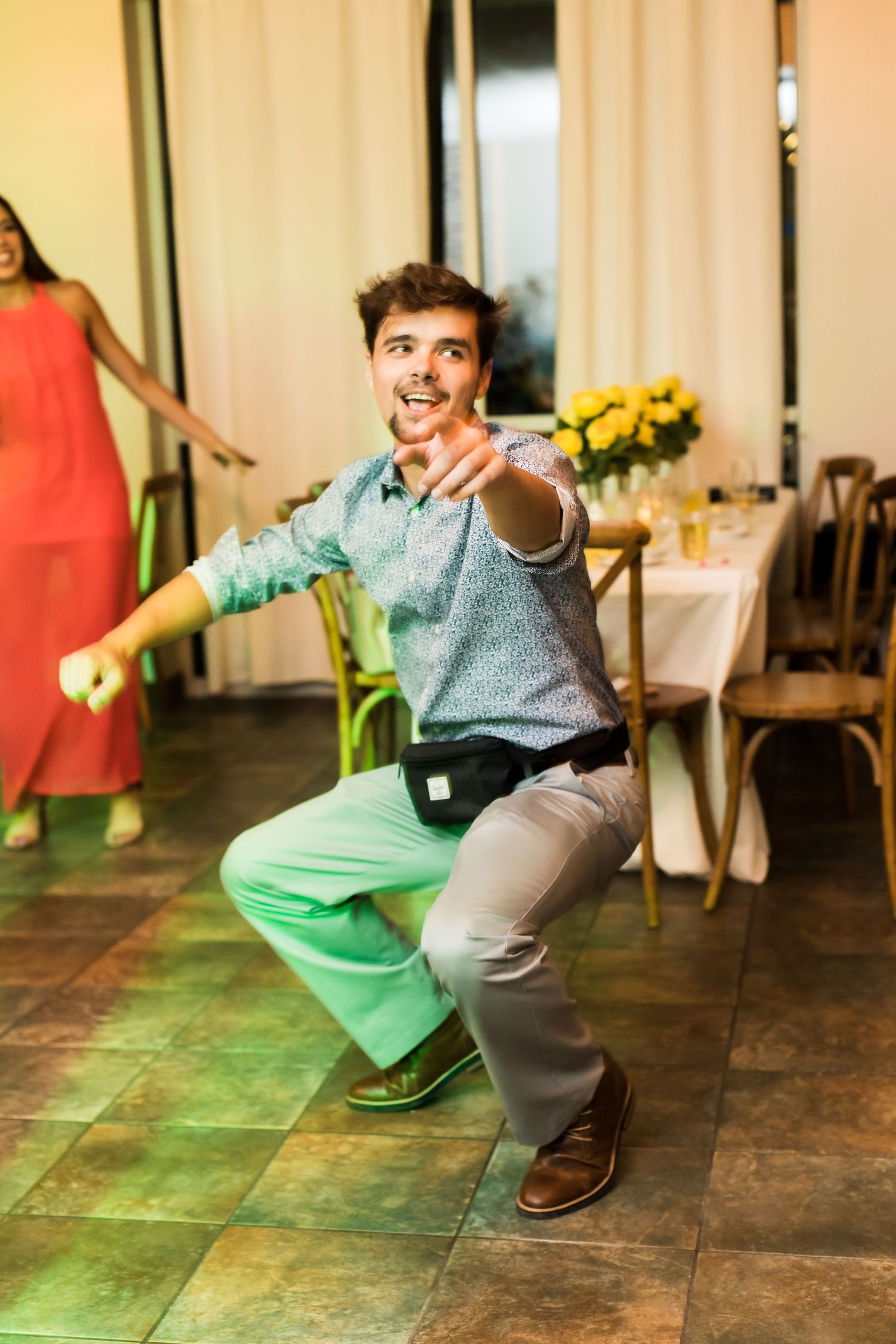 Wedding guest dances energetically in casual attire during reception celebration.