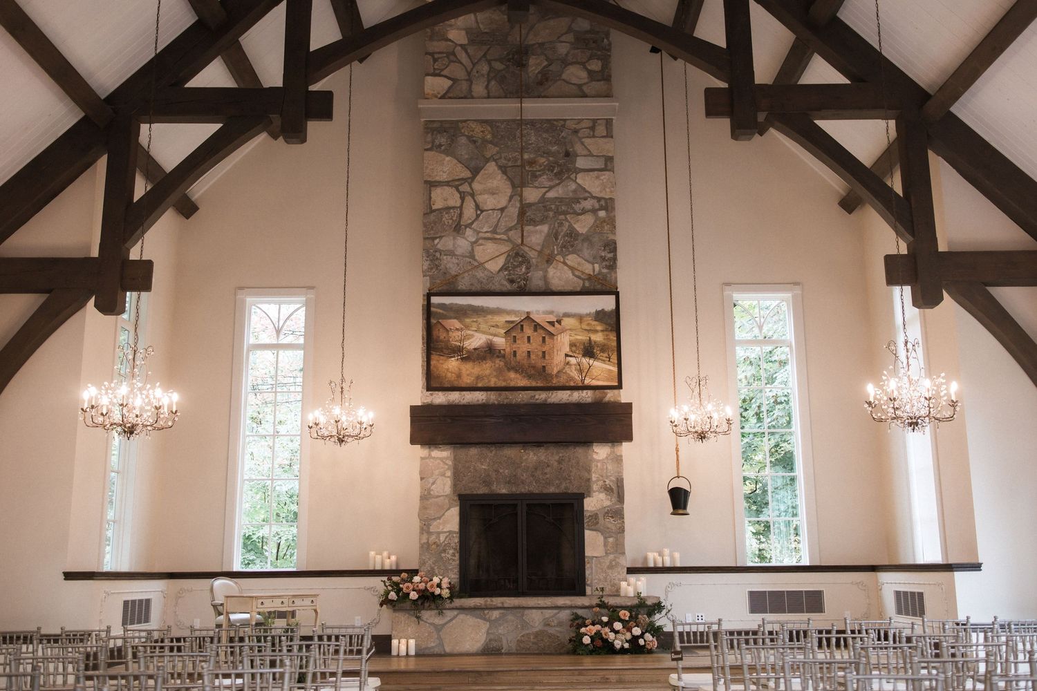 Chapel-style wedding venue with vaulted ceiling, stone fireplace, and rows of white chairs.