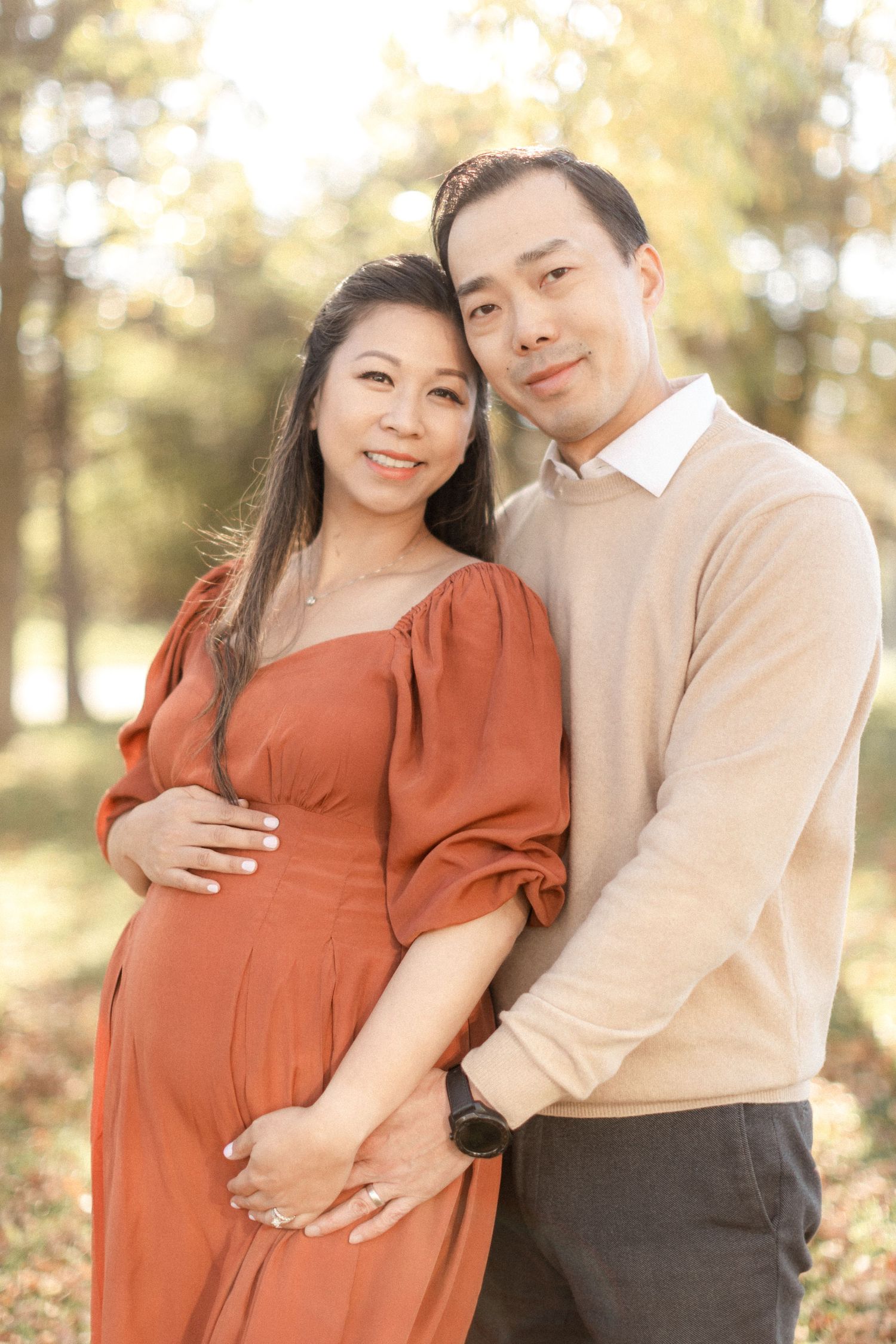 Outdoor maternity portrait with warm lighting and fall foliage background.
