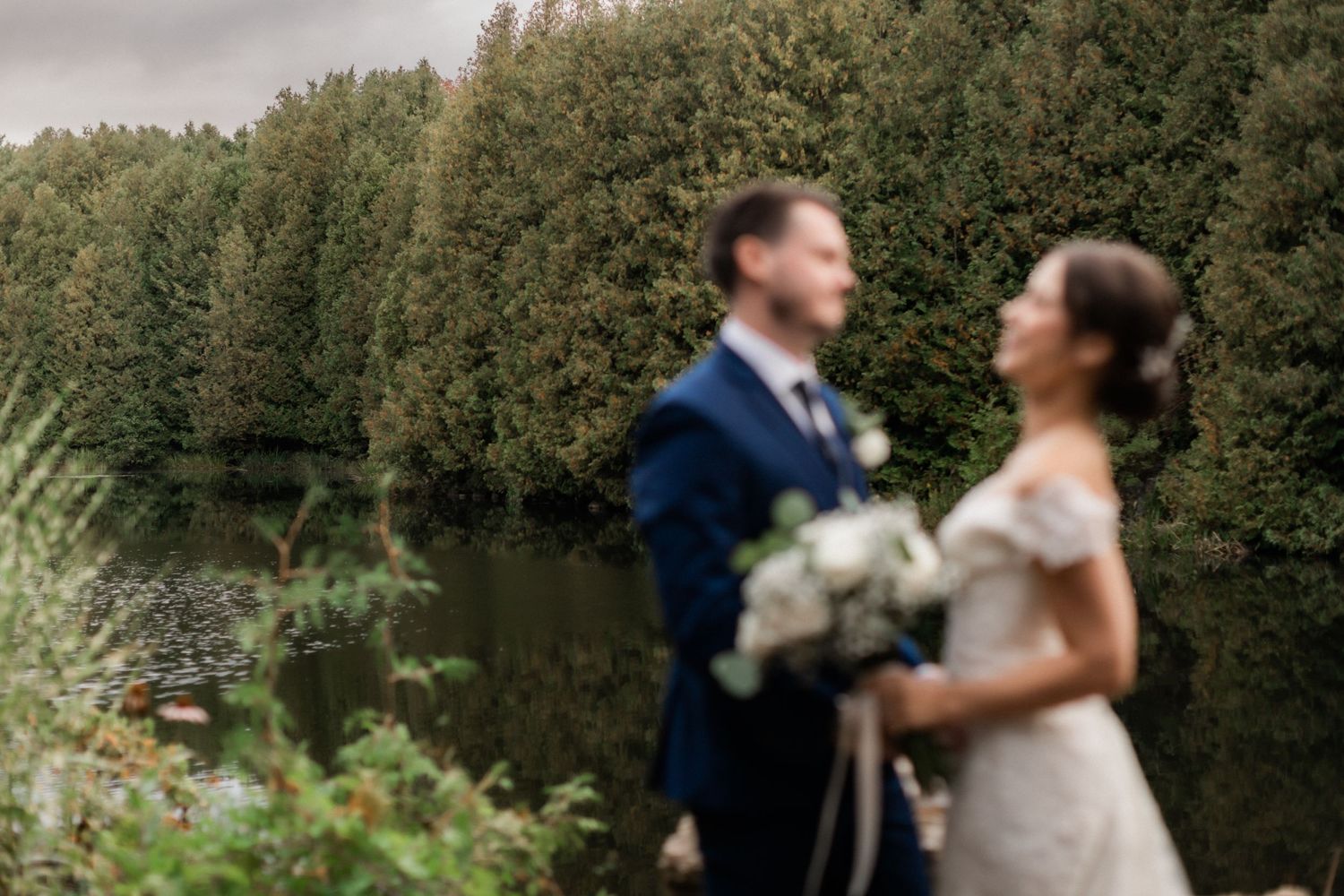 An artistic blurred wedding photo capturing a couple's intimate moment by a lake.