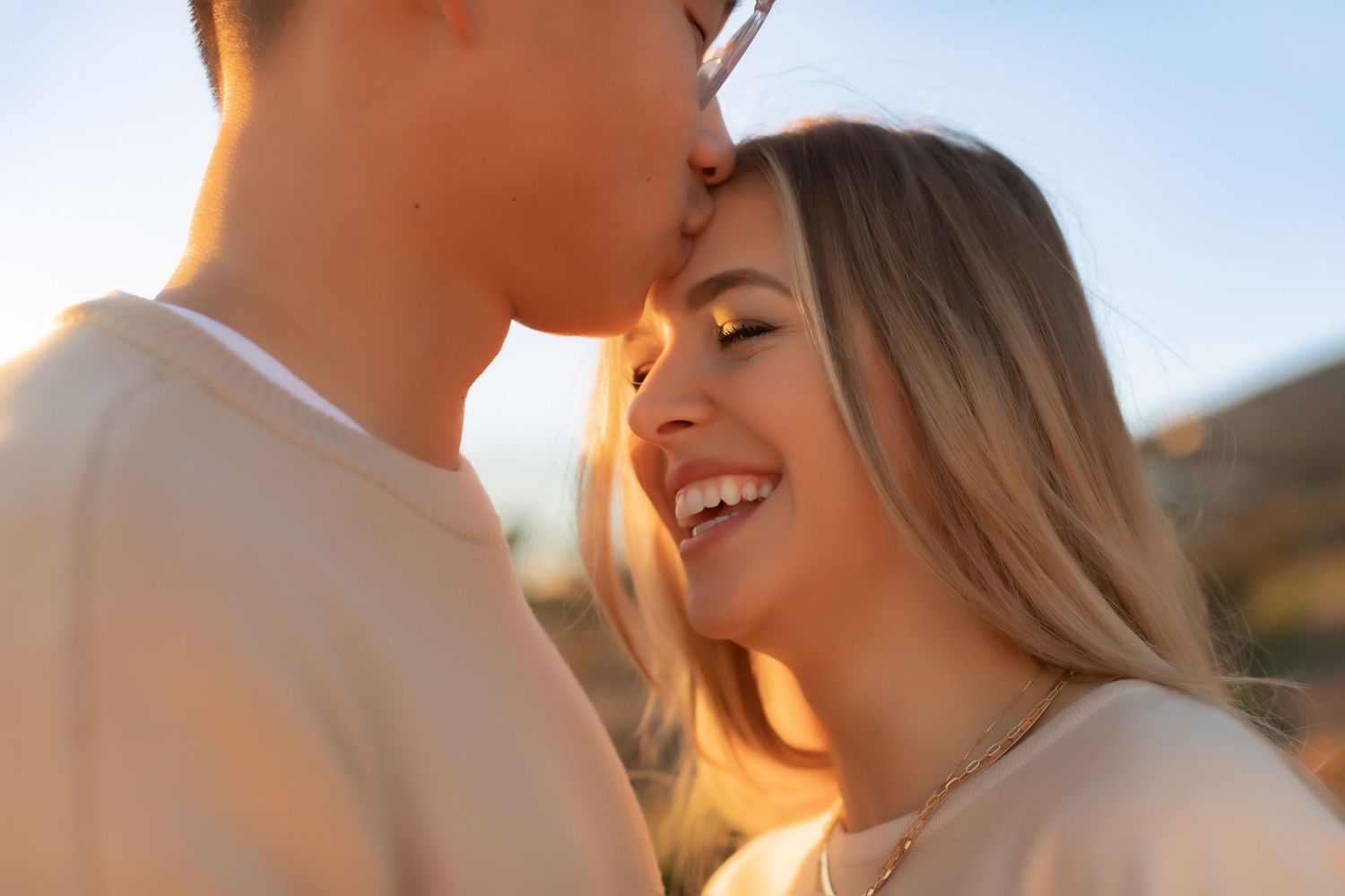 Close-up of joyful couple sharing tender moment against ocean sunset backdrop.