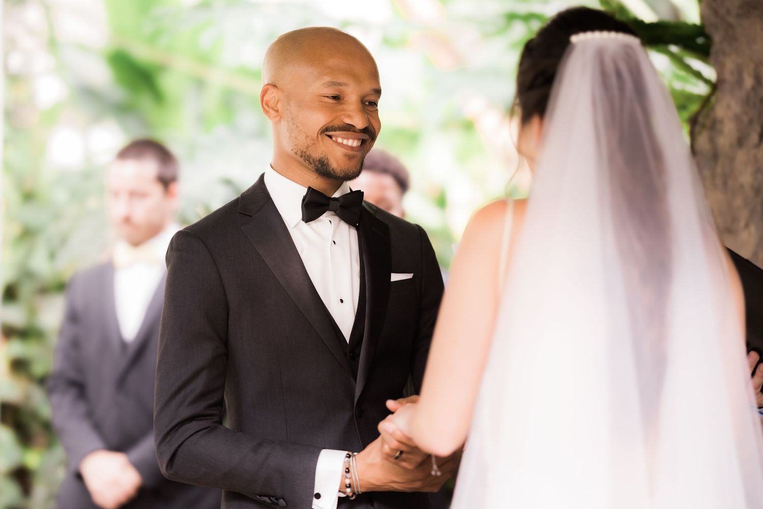 A joyful wedding ceremony moment captured under garden greenery.