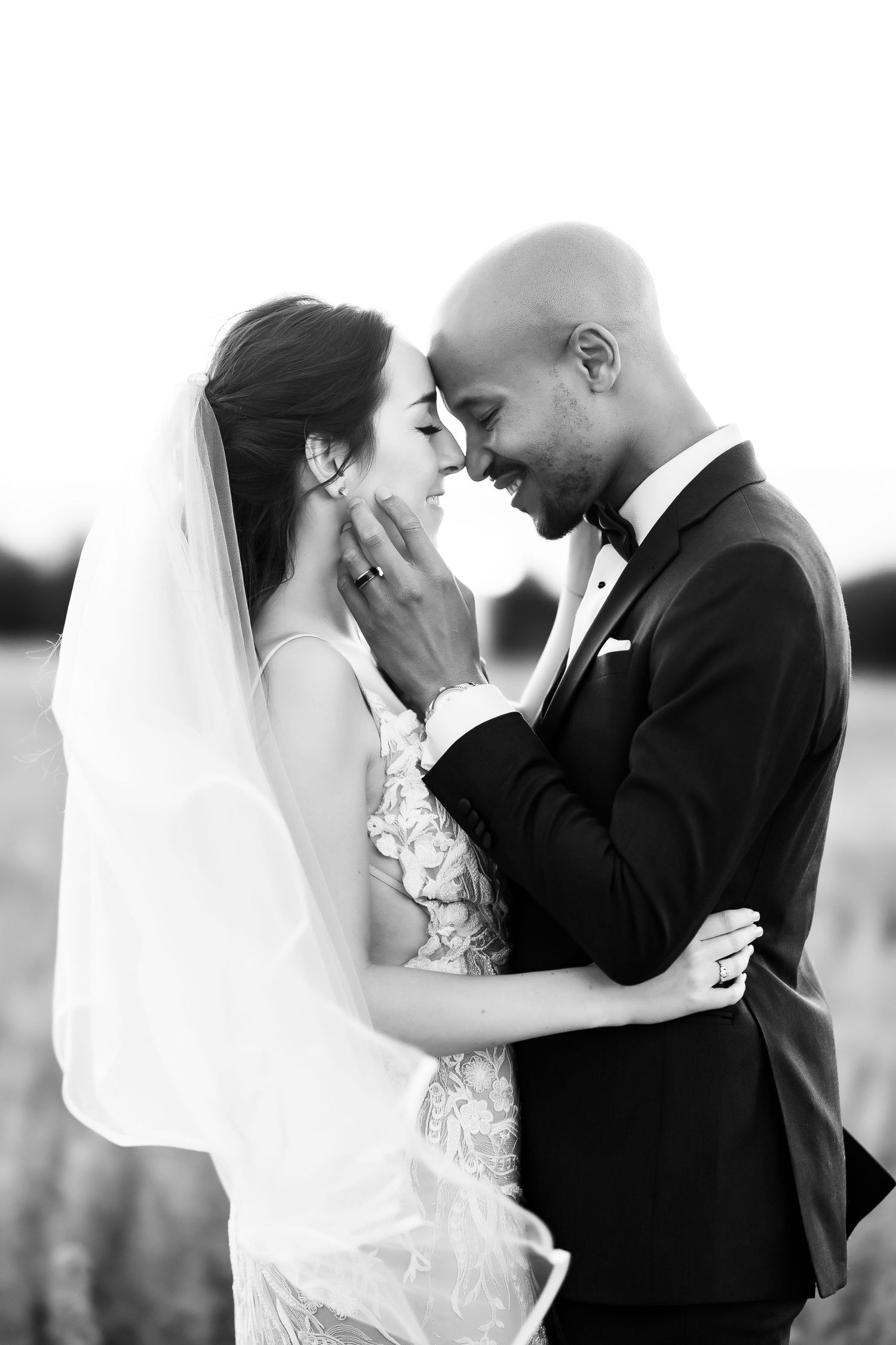 Black and white portrait of newlyweds sharing an intimate moment outdoors.