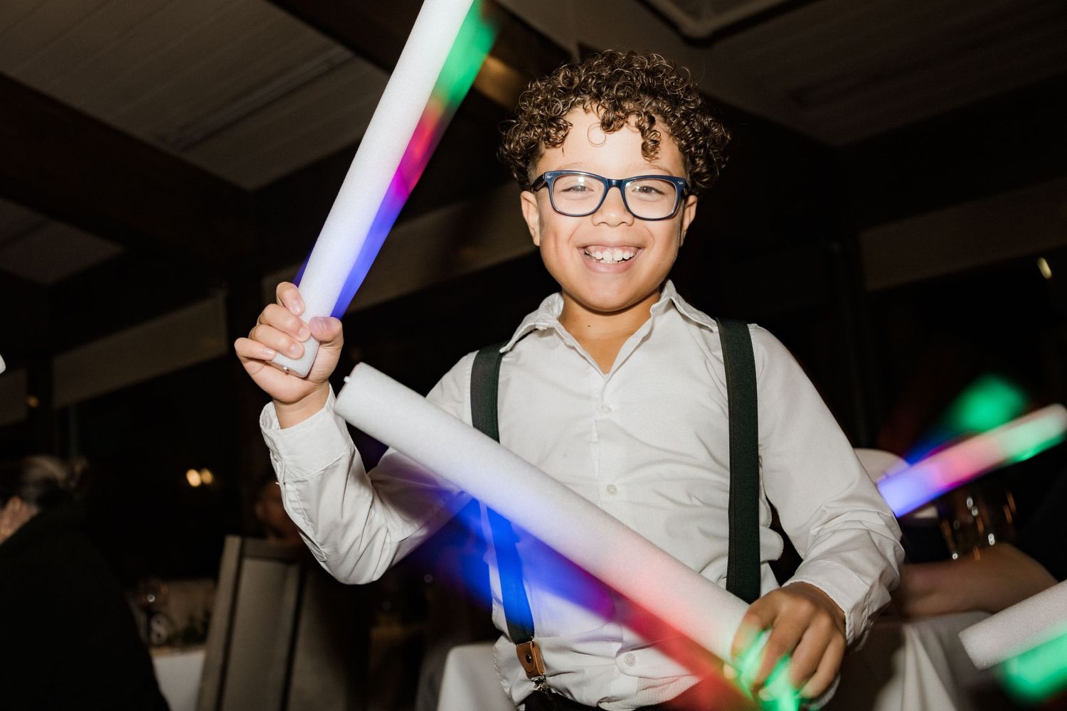Young guest enjoying a wedding reception while holding LED foam light sticks.