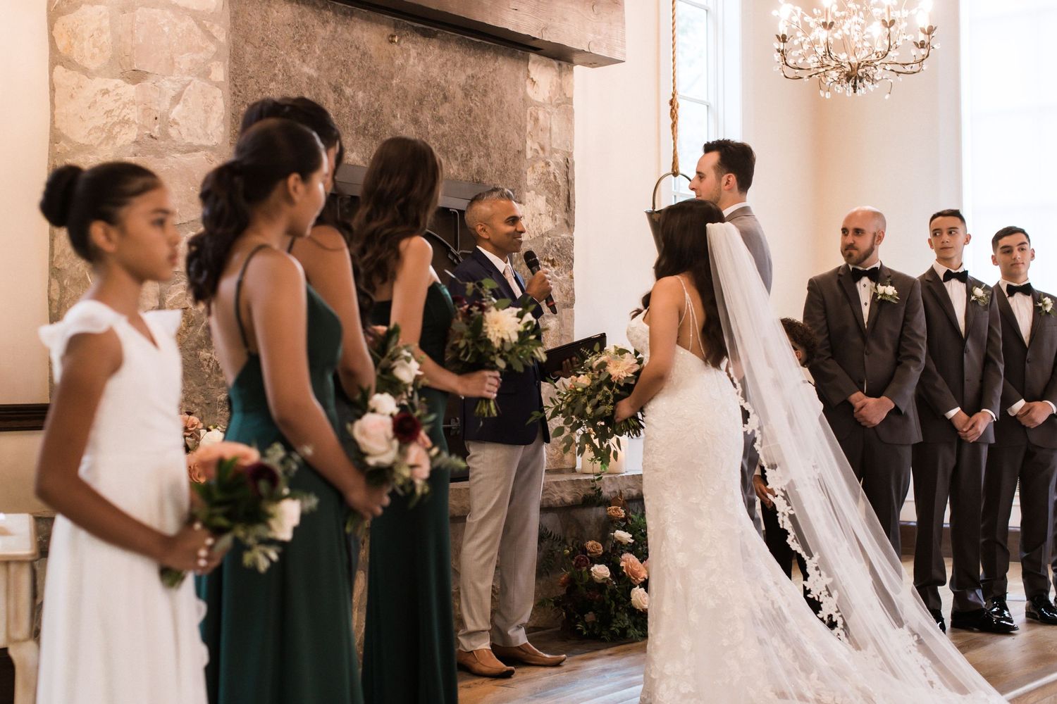 Wedding ceremony with bridesmaids in white and green dresses standing beside bride.