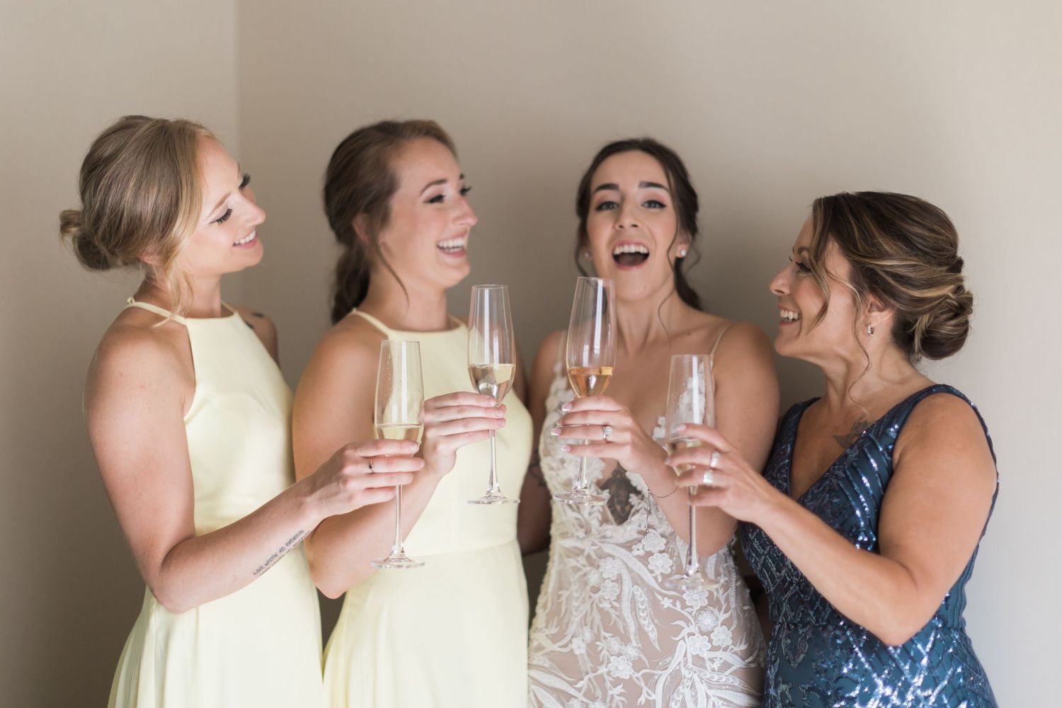 A celebratory moment with bridesmaids in yellow and blue dresses toasting with champagne glasses.
