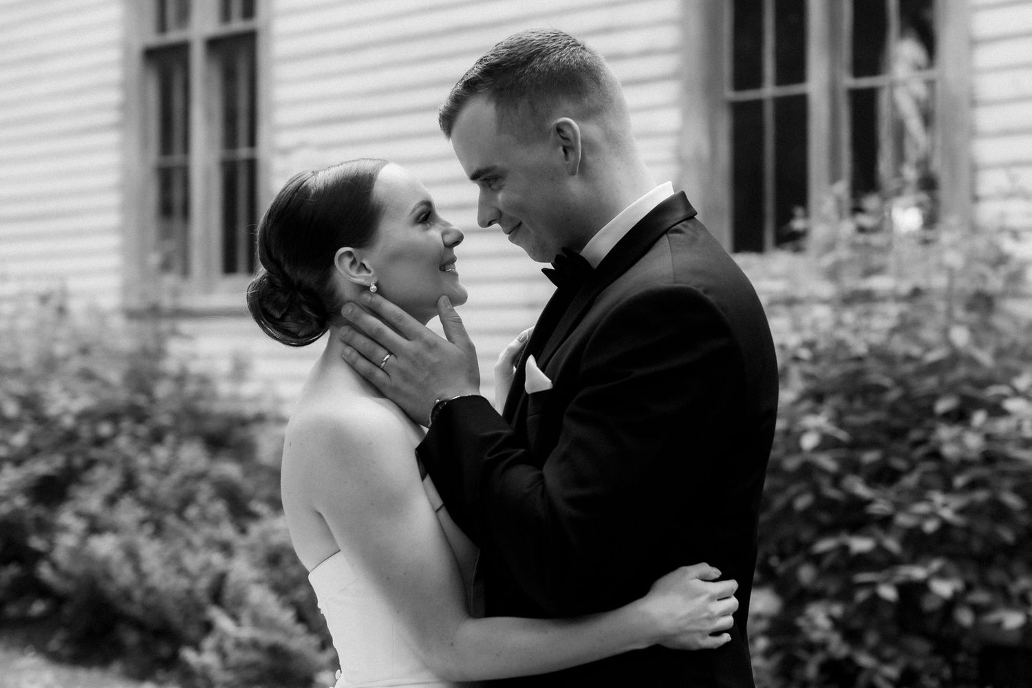Black and white intimate portrait of a couple sharing a romantic moment outdoors.
