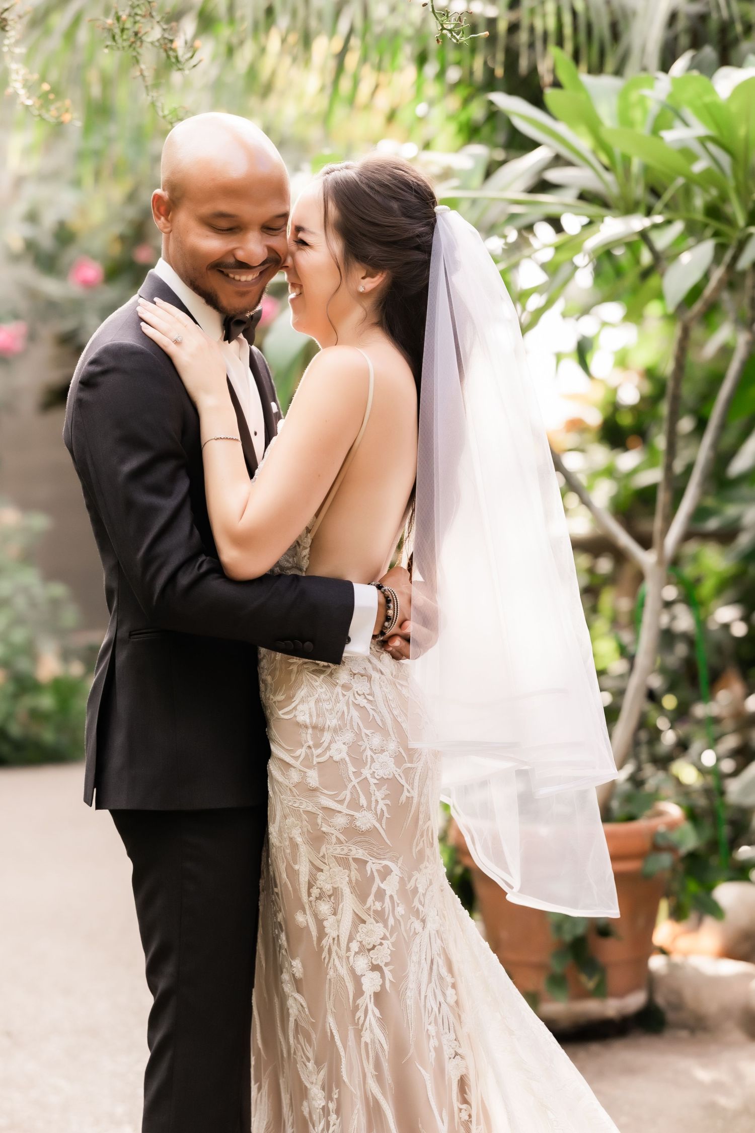 Couple sharing an intimate moment during their wedding photoshoot in a tropical garden.