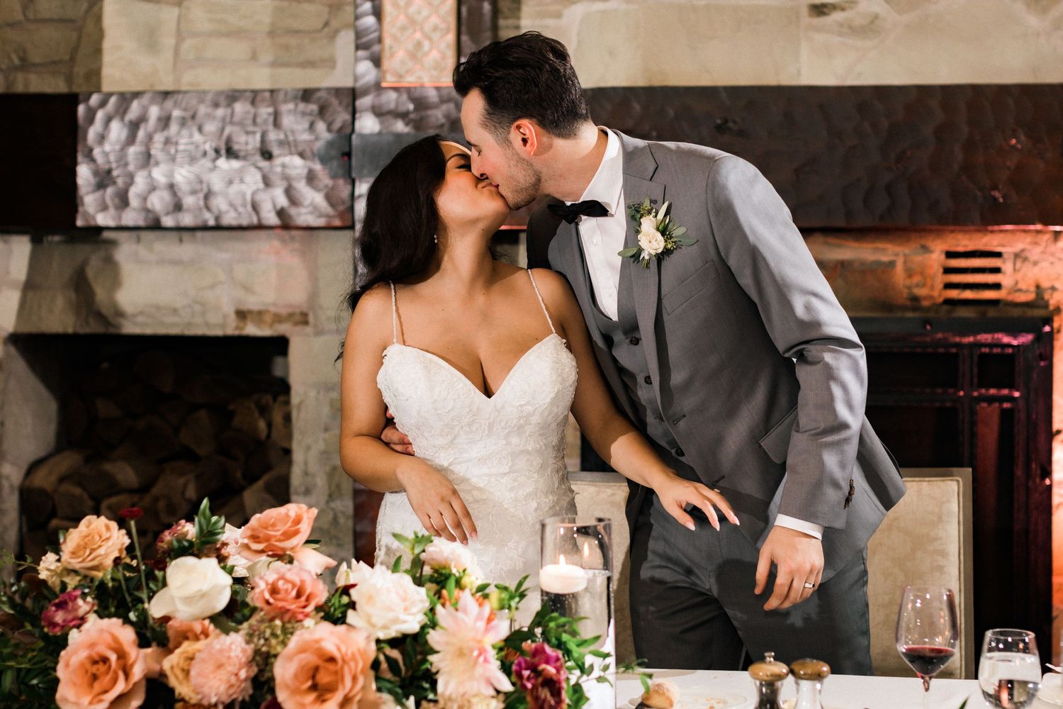 Romantic moment shared at wedding reception with elegant peach and white floral arrangements.