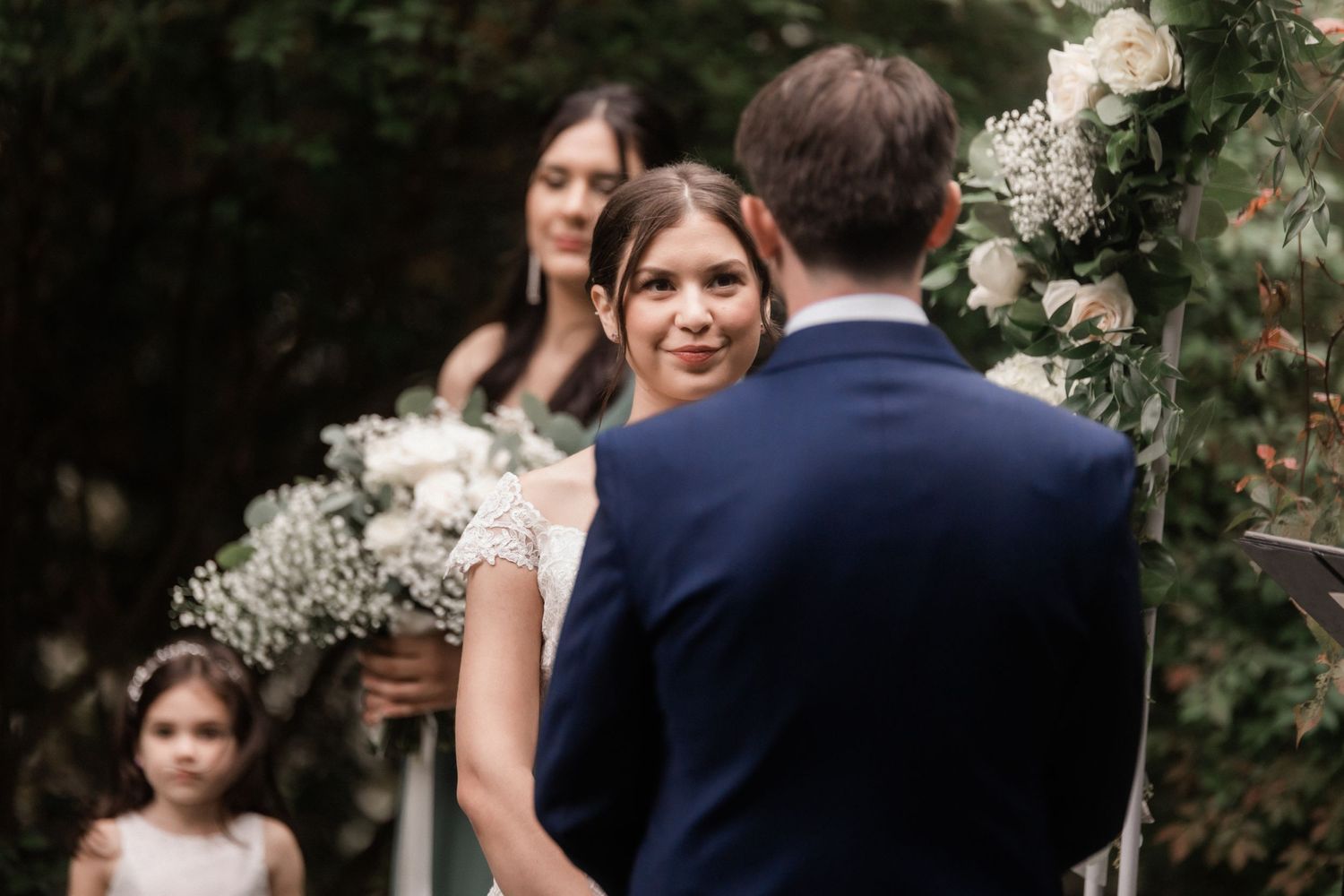 Emotional wedding ceremony moment captured under floral decorations in a garden setting.