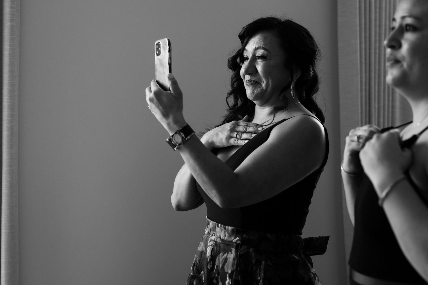 Guest capturing wedding moments on smartphone in black and white photography.