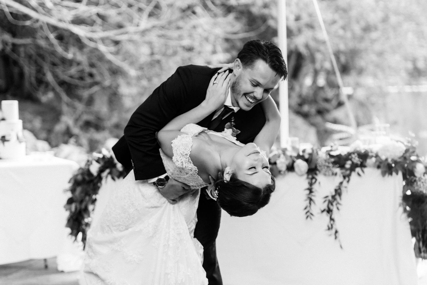 Playful black and white photo of couple dancing with dramatic dip move.
