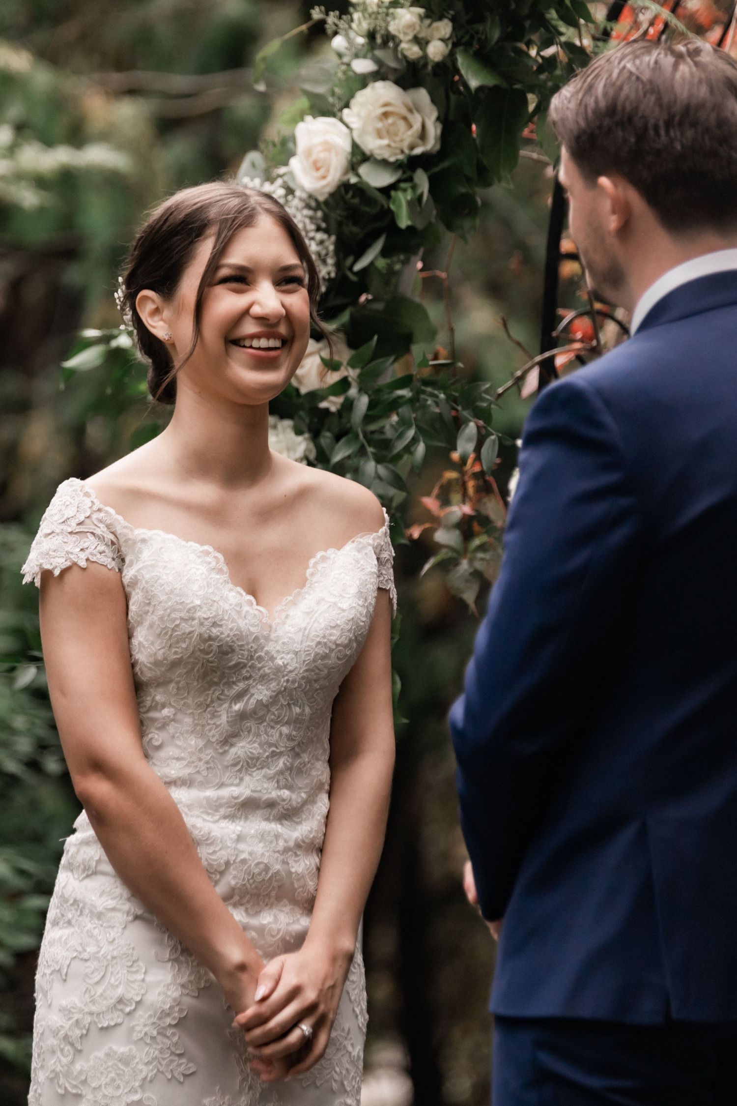 An intimate wedding moment captured with white roses and greenery in the background.