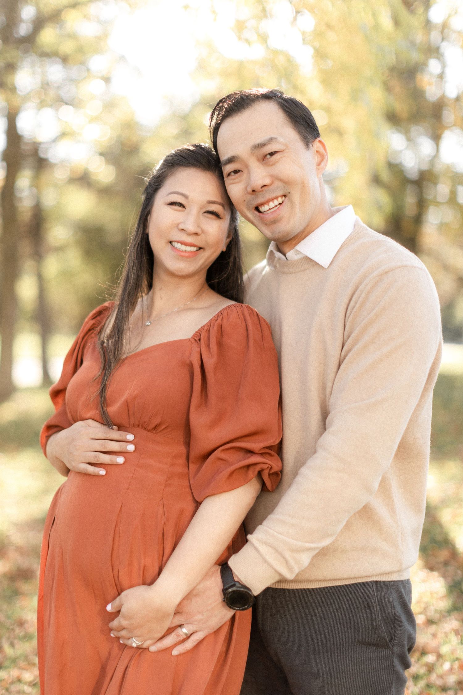 Joyful couple shares sweet moment during autumn maternity photoshoot.