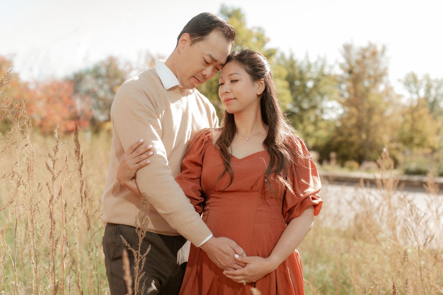 An intimate maternity photo of a couple embracing in golden afternoon light.