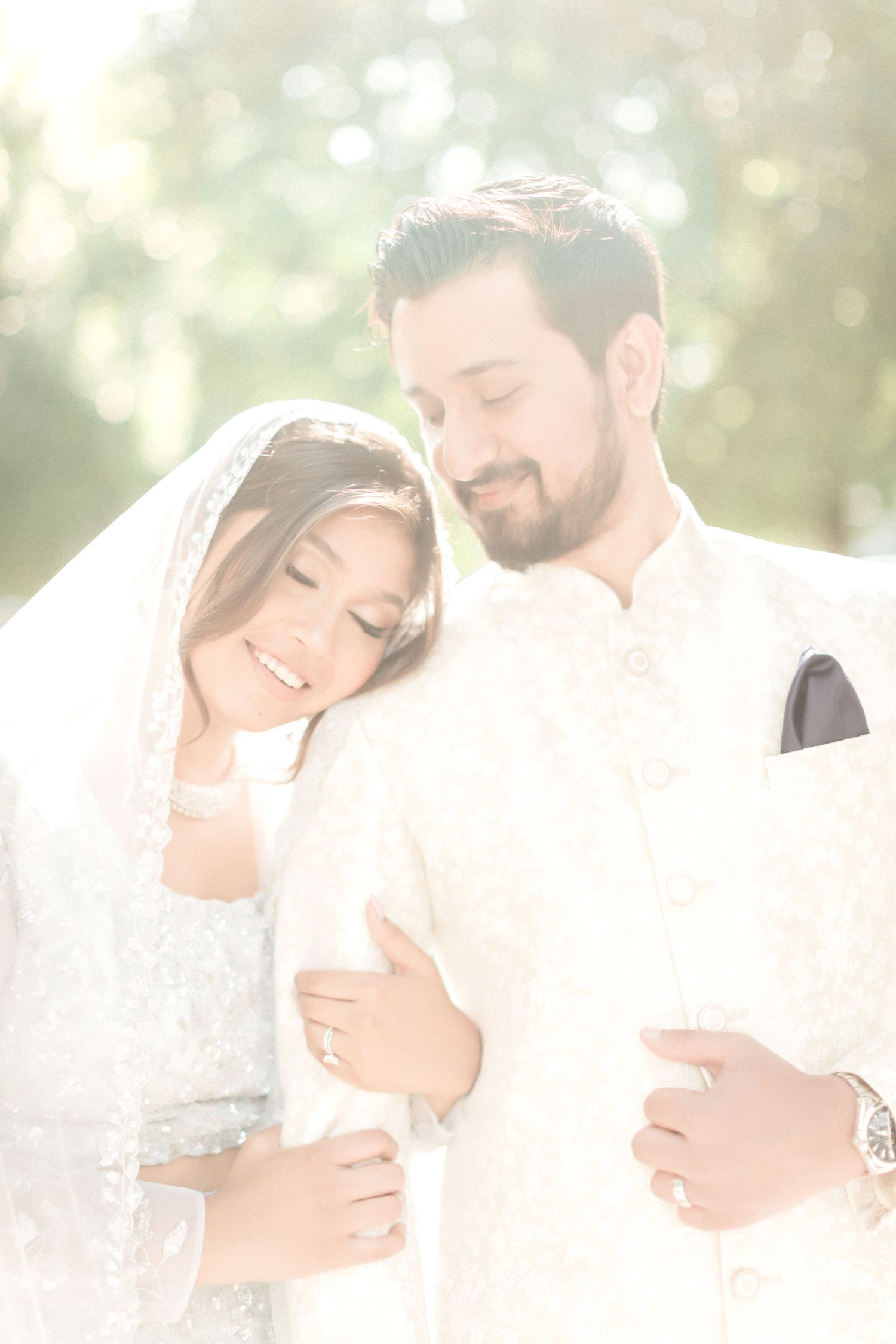 Dreamy sunlit portrait of couple sharing tender moment under bridal veil.