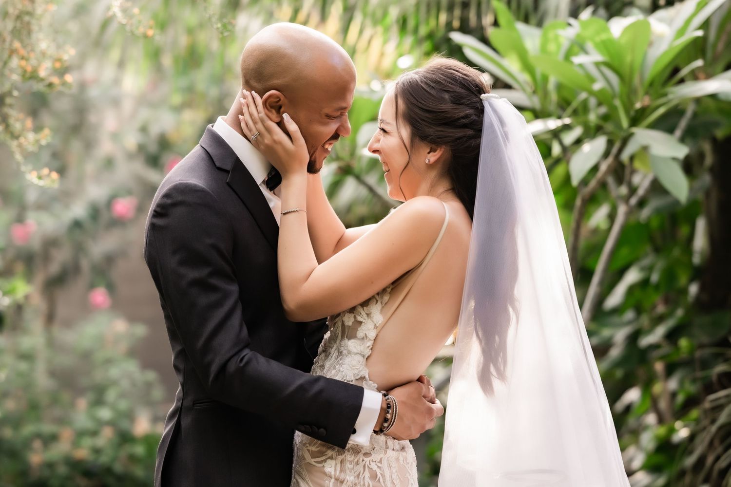 Bride and groom share emotional moment during wedding ceremony in tropical garden setting.