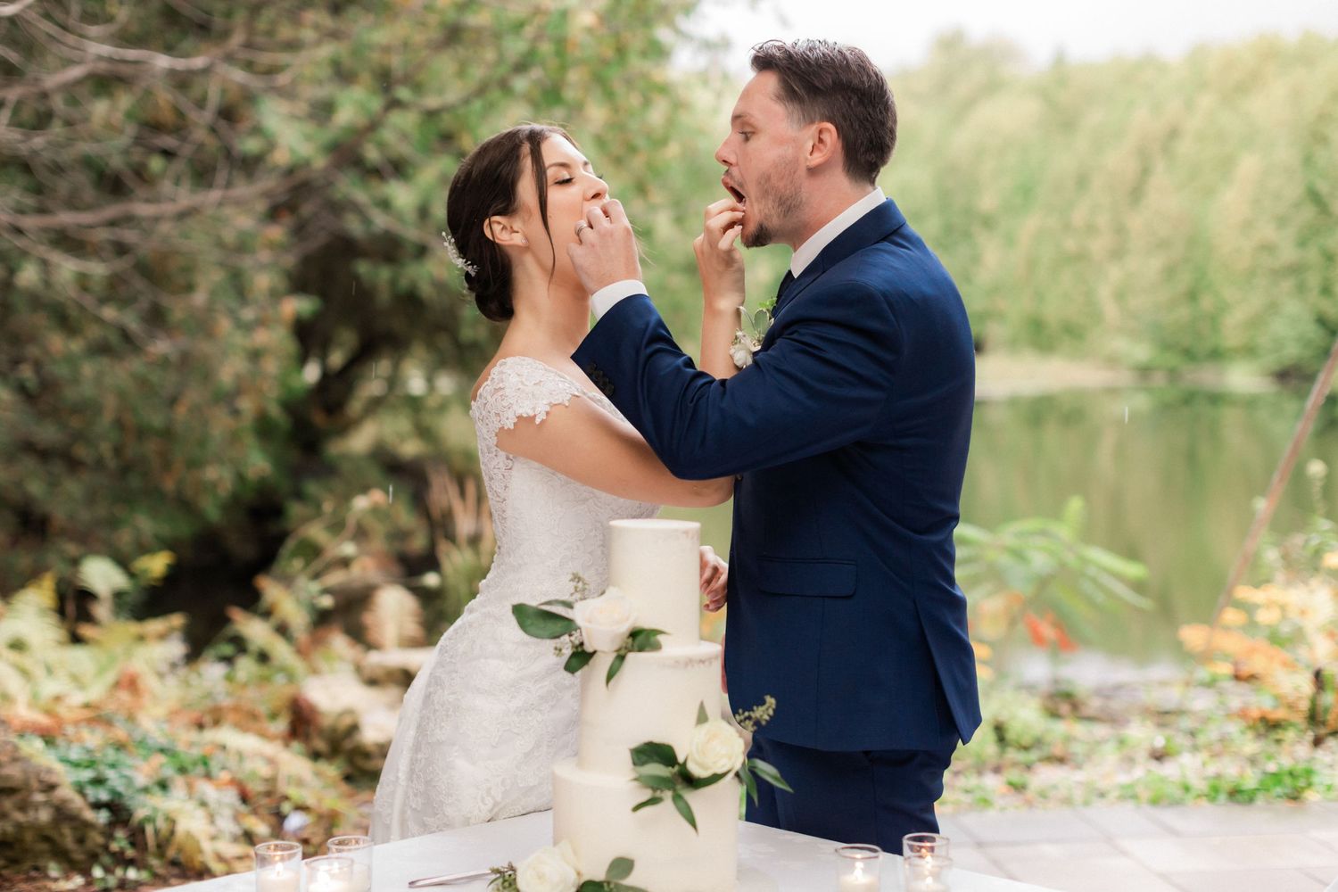 Romantic outdoor wedding portrait by lake with couple in classic attire.