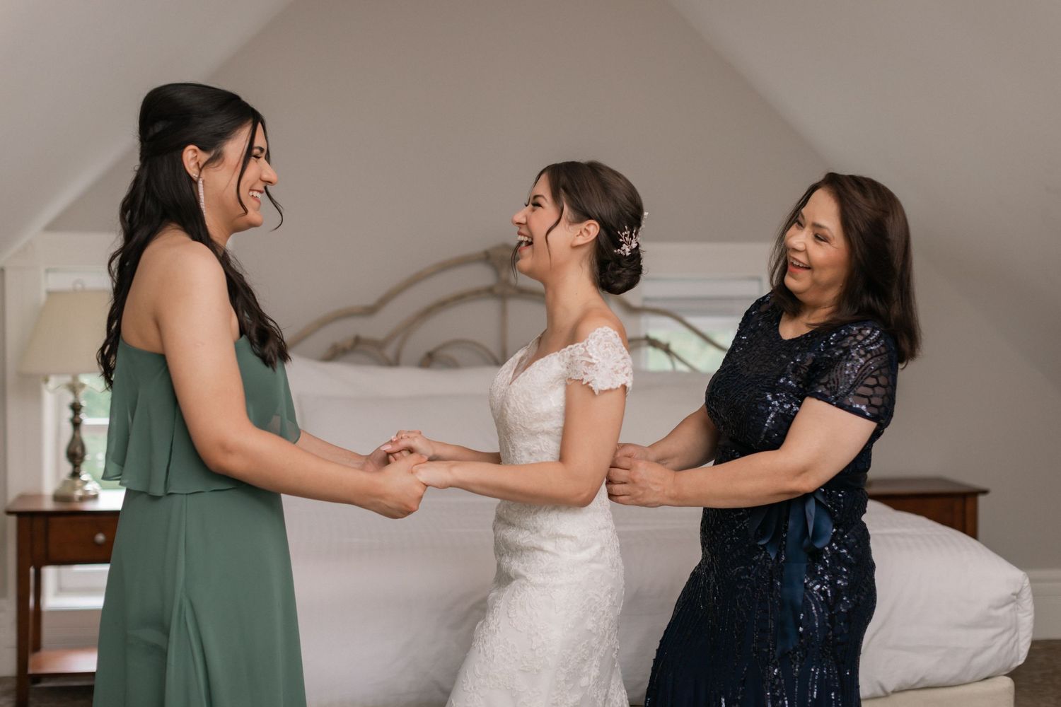 Three people share a joyful moment in formal attire during wedding preparations.