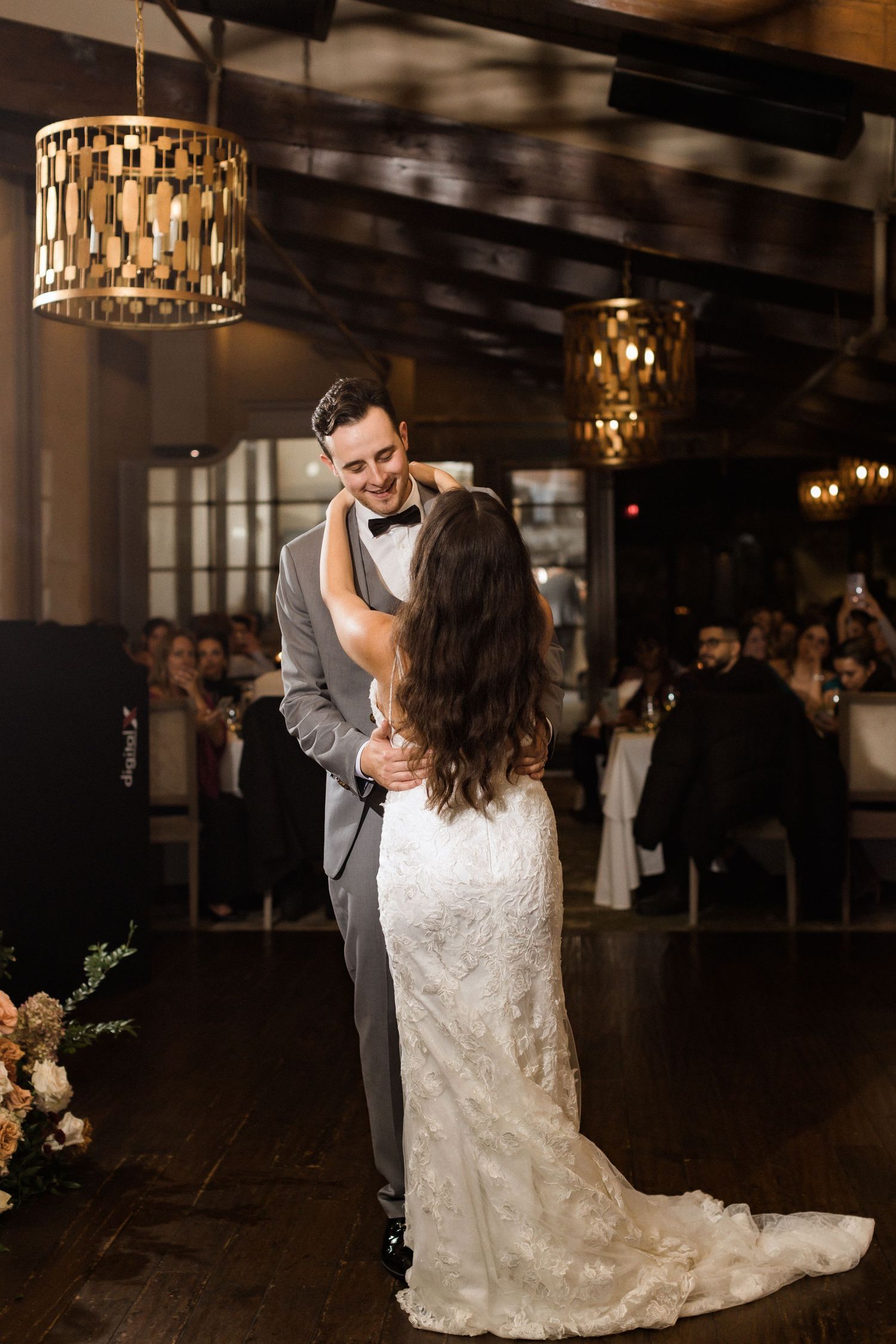 A couple shares their first dance in an elegant venue with geometric pendant lighting.