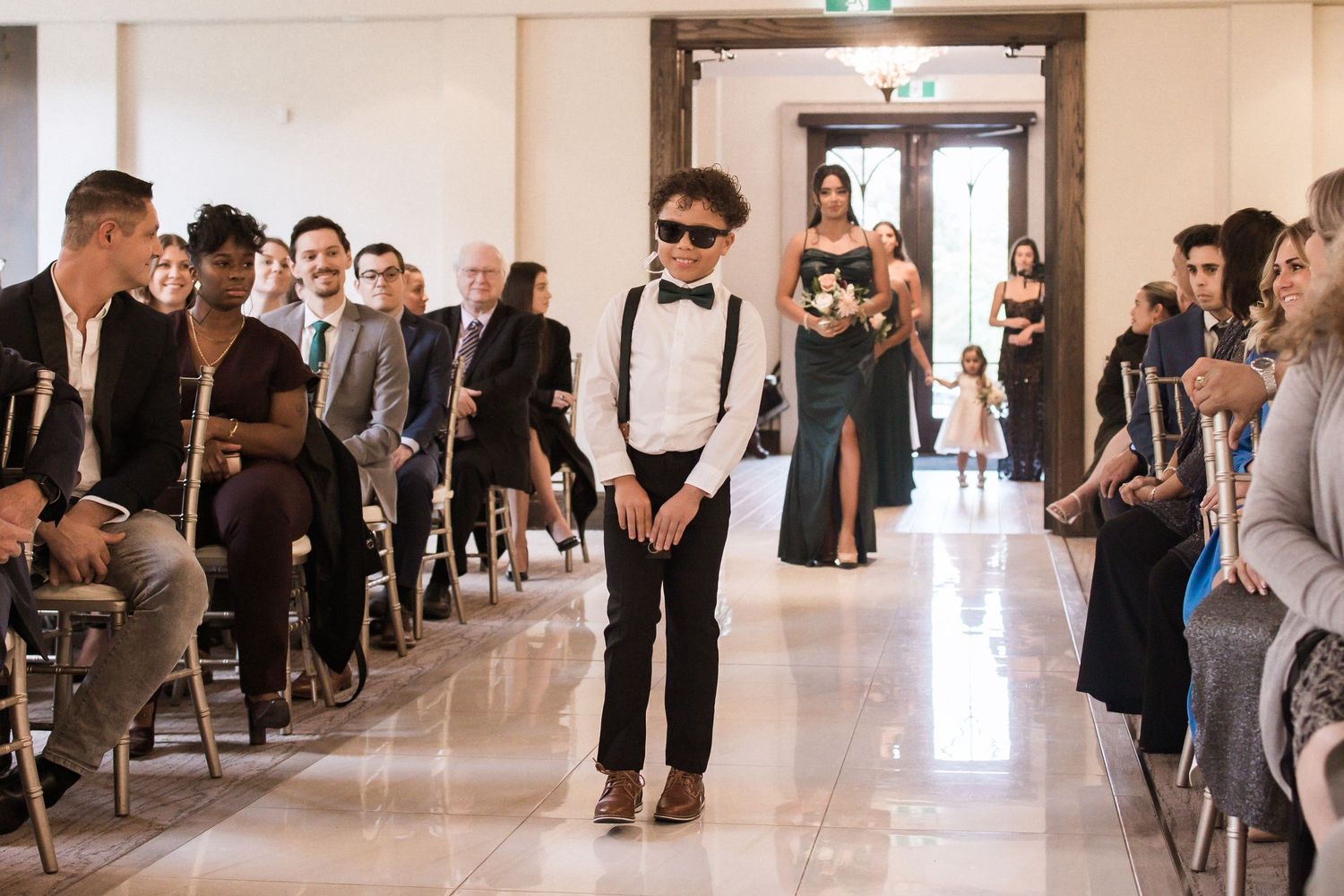 Wedding ceremony in a bright chapel with guests seated along the center aisle.