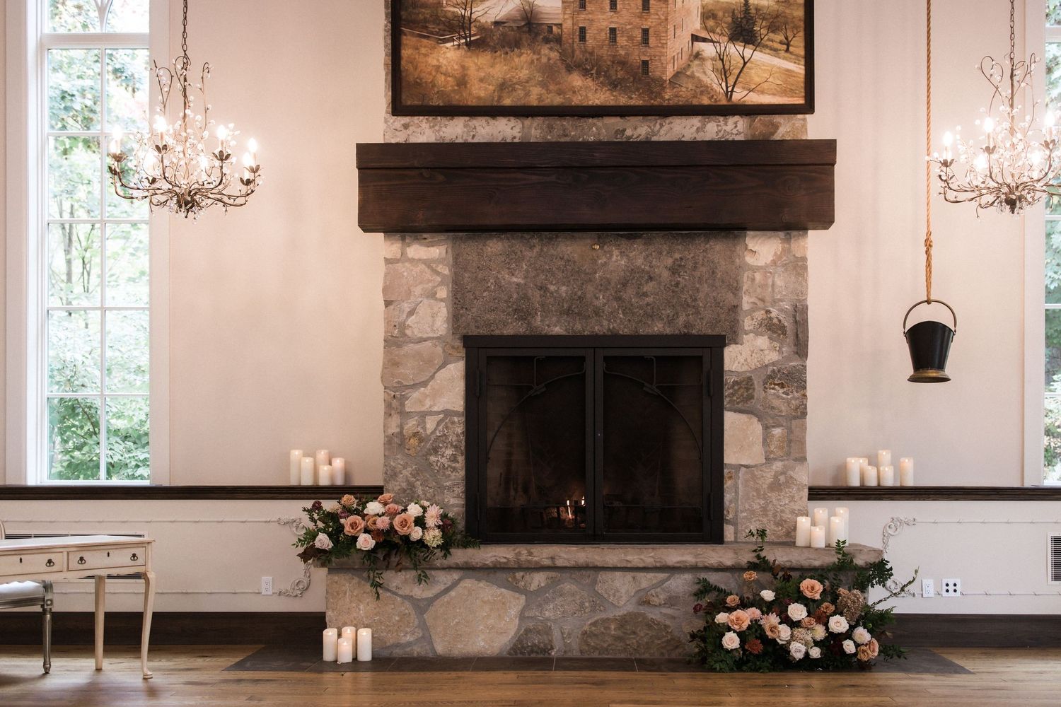Stone fireplace decorated with flowers and candles in an elegant white room.