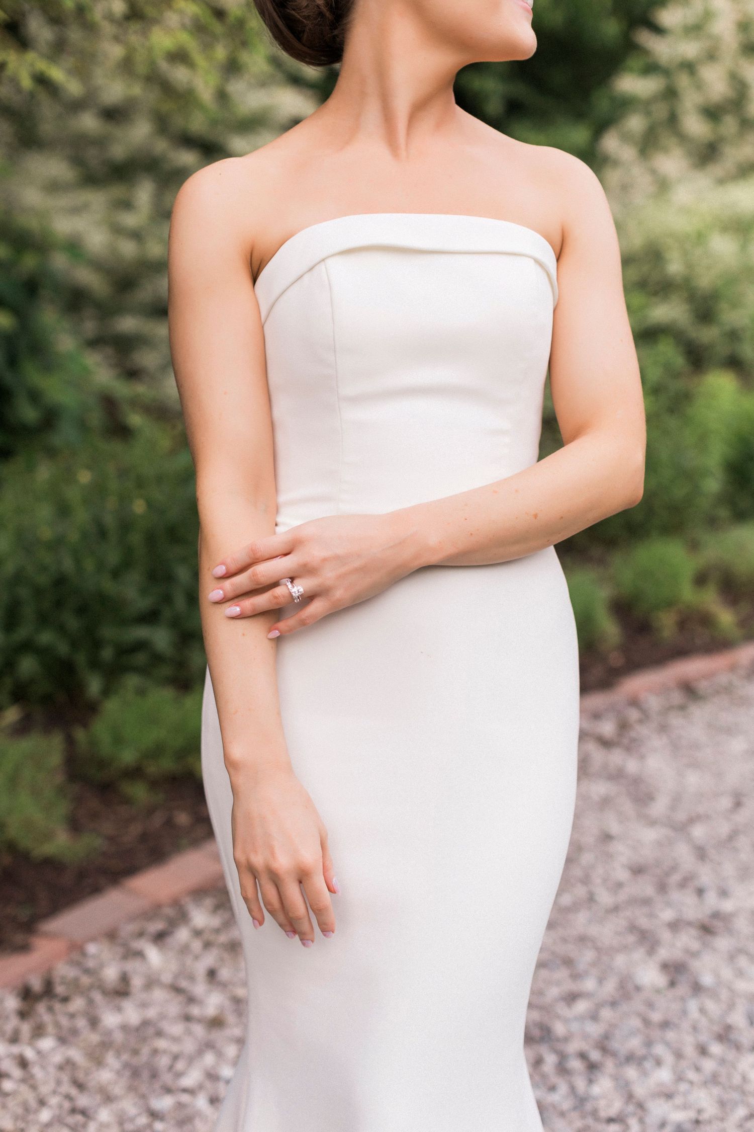 Close-up detail of strapless white wedding dress showing elegant minimal design.