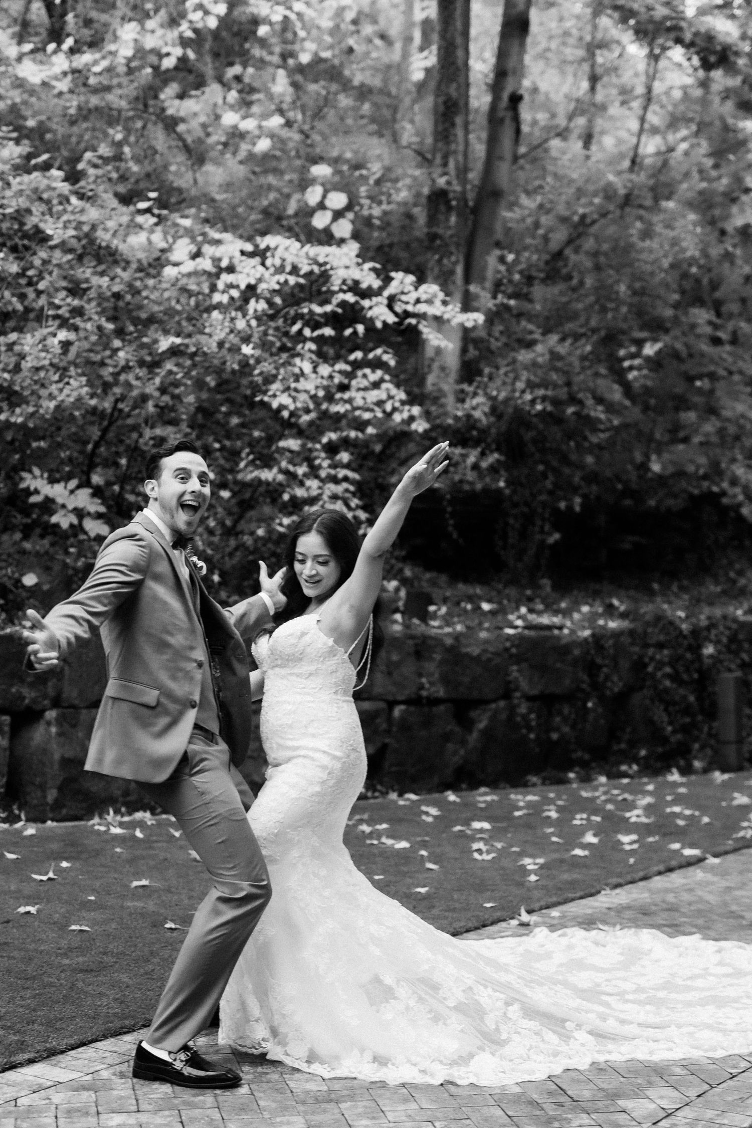 A joyful black and white photo of newlyweds dancing together on their wedding day.