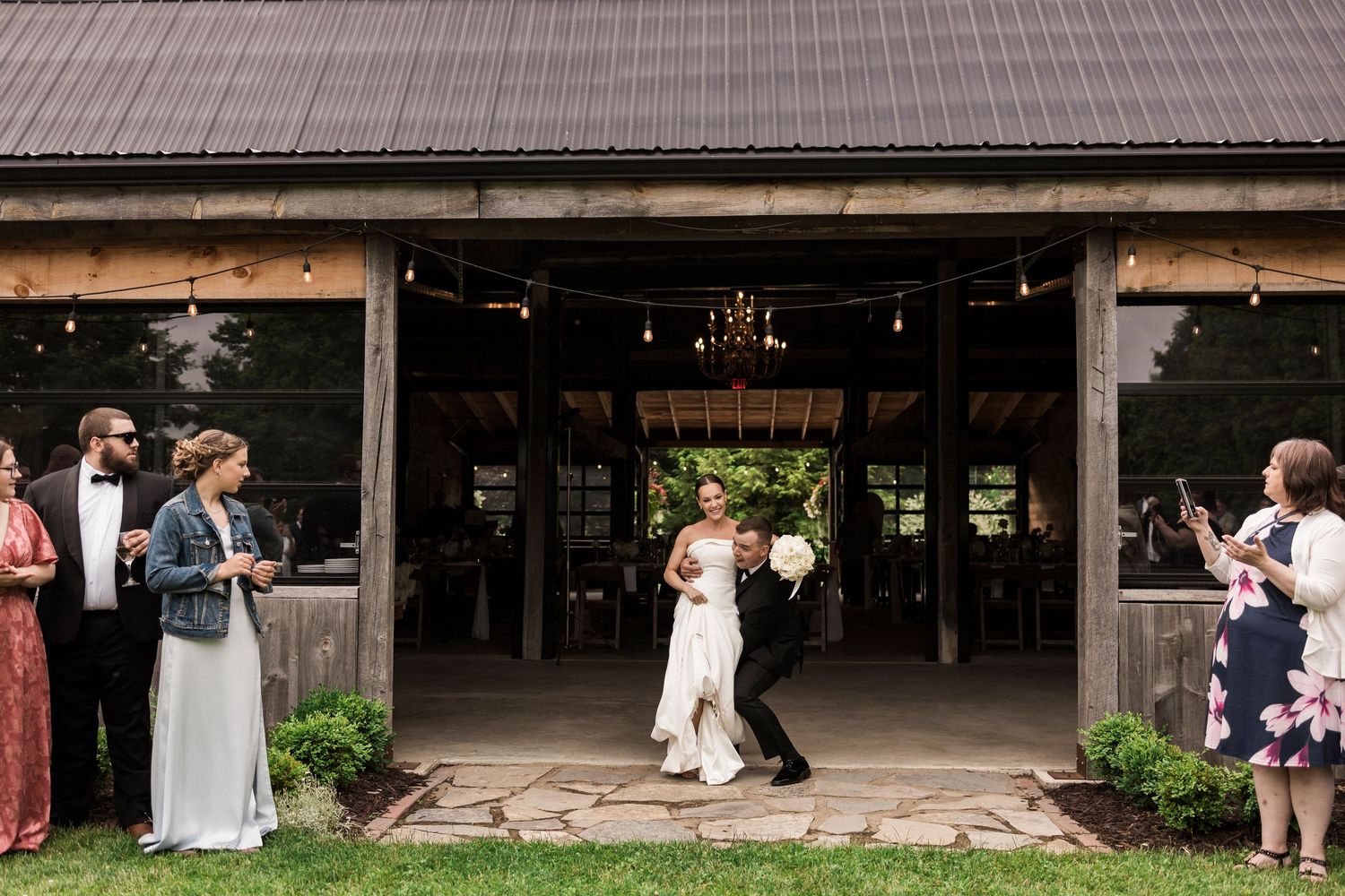 Elegant outdoor rustic barn wedding ceremony space with wooden benches and natural forest surroundings in muted tones.