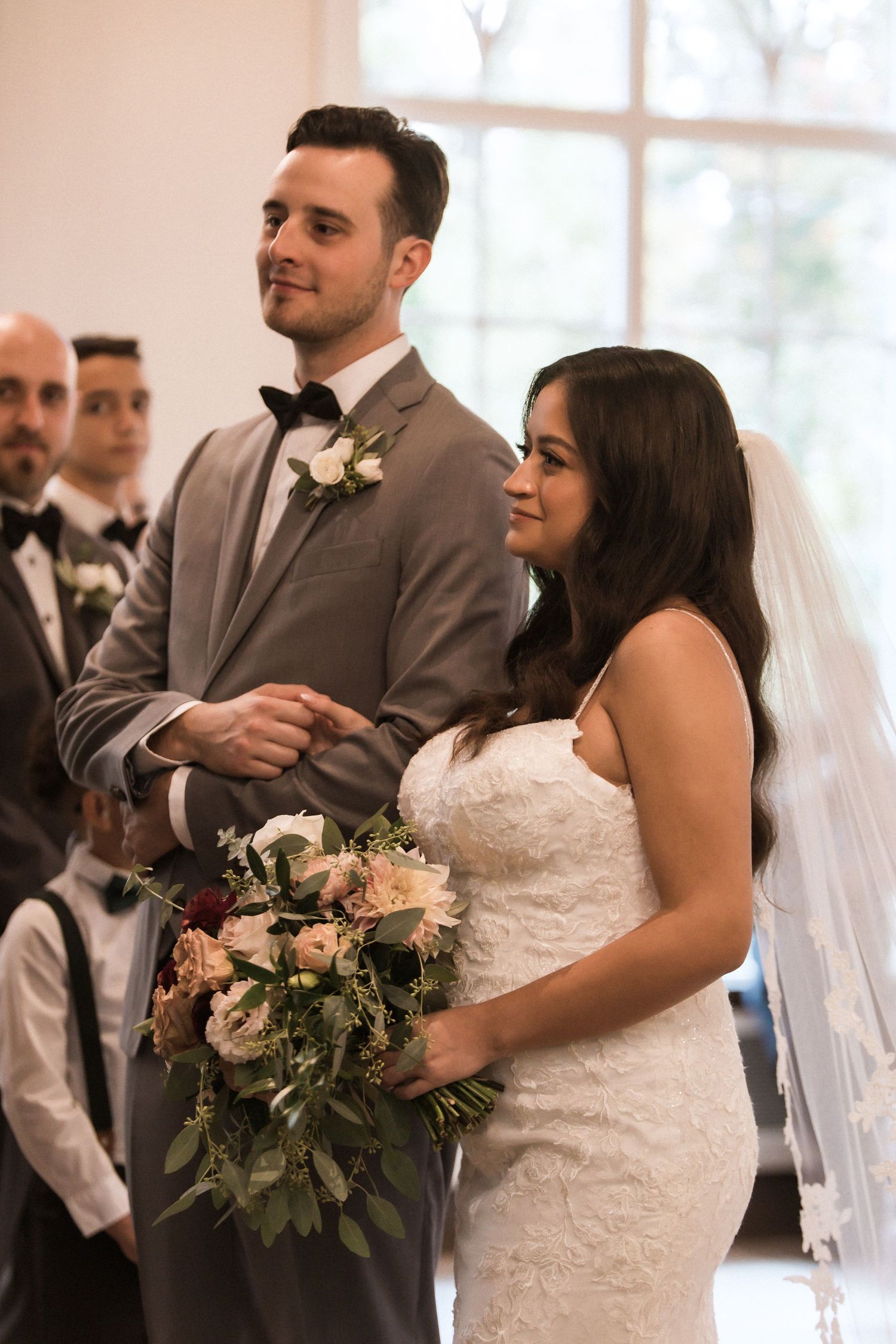 A tender moment captured during a wedding ceremony in a sunlit room with elegant decor.