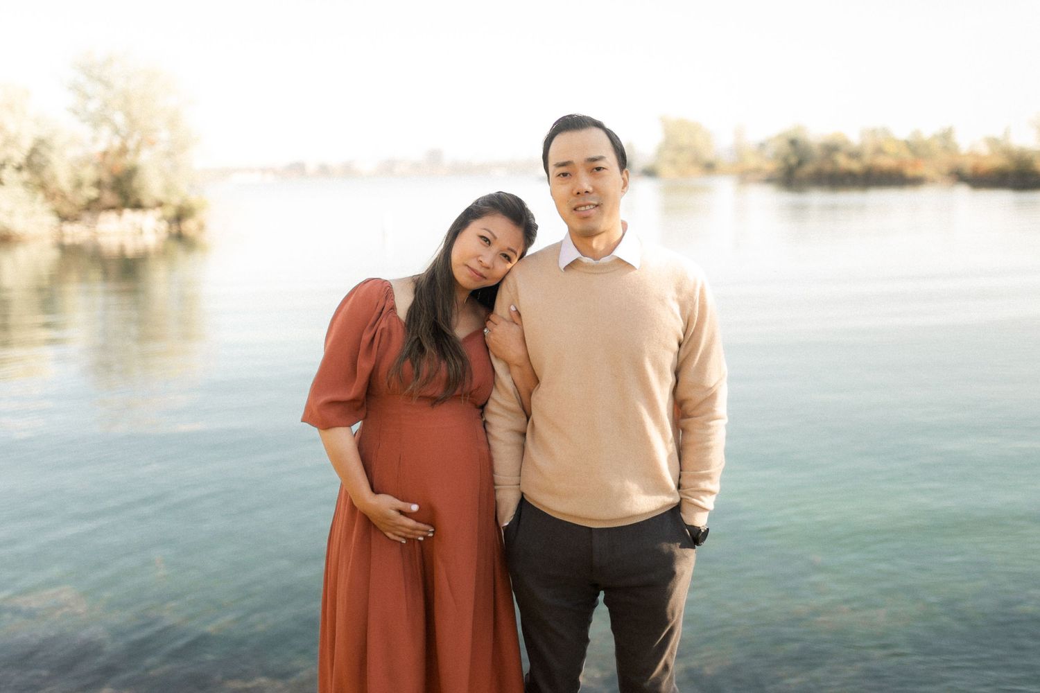 Intimate maternity portrait of couple against serene lake backdrop.