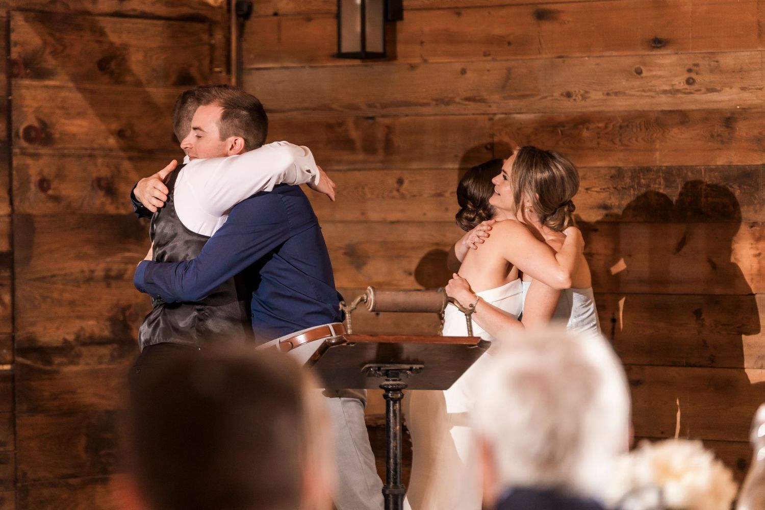 Emotional moment shared between wedding guests during reception in rustic wooden venue.