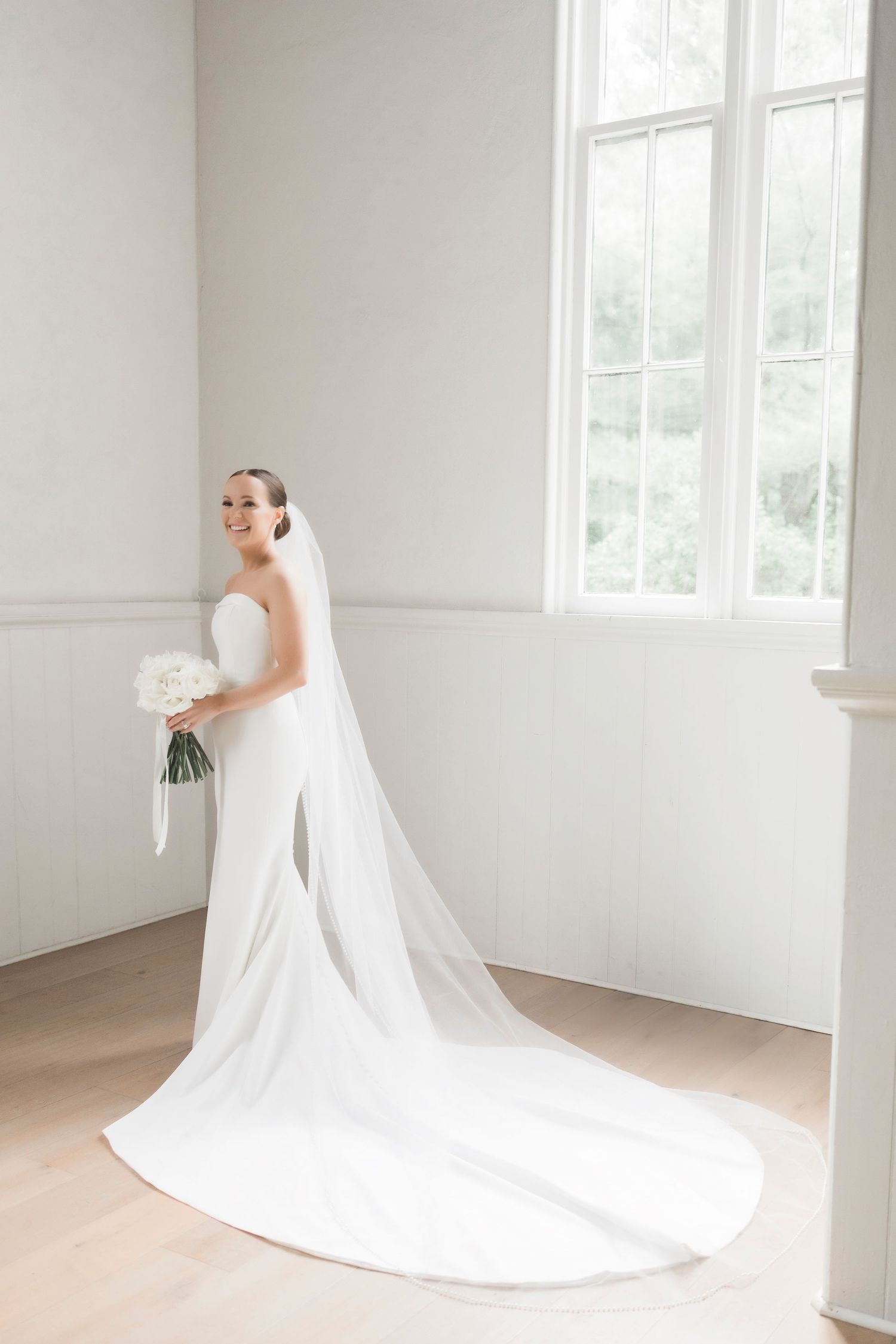An elegant wedding dress with a flowing train captured in a minimalist white chapel setting.