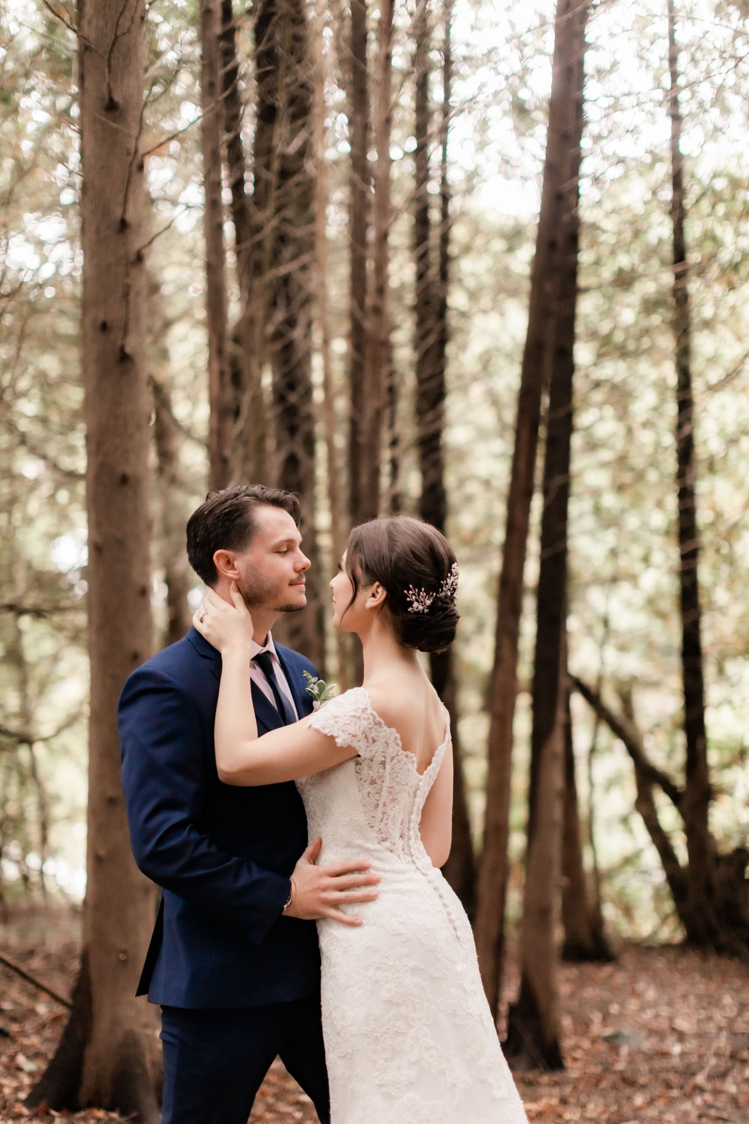 Intimate wedding portrait of newlyweds embracing in a serene forest setting.
