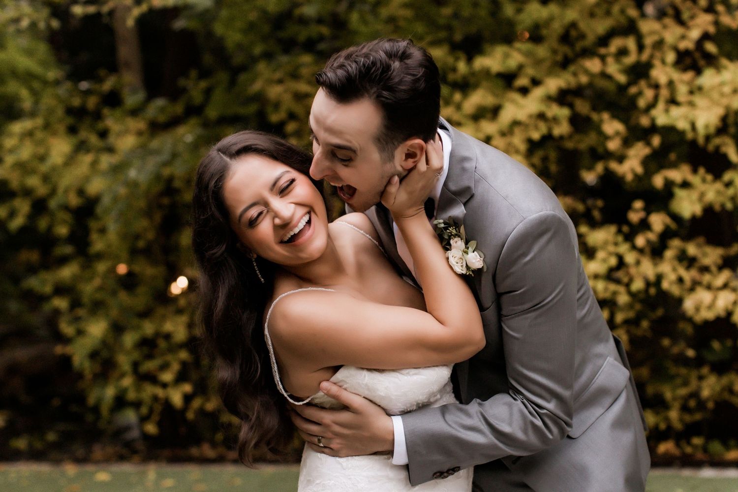 Joyful candid moment between newlyweds in garden setting.