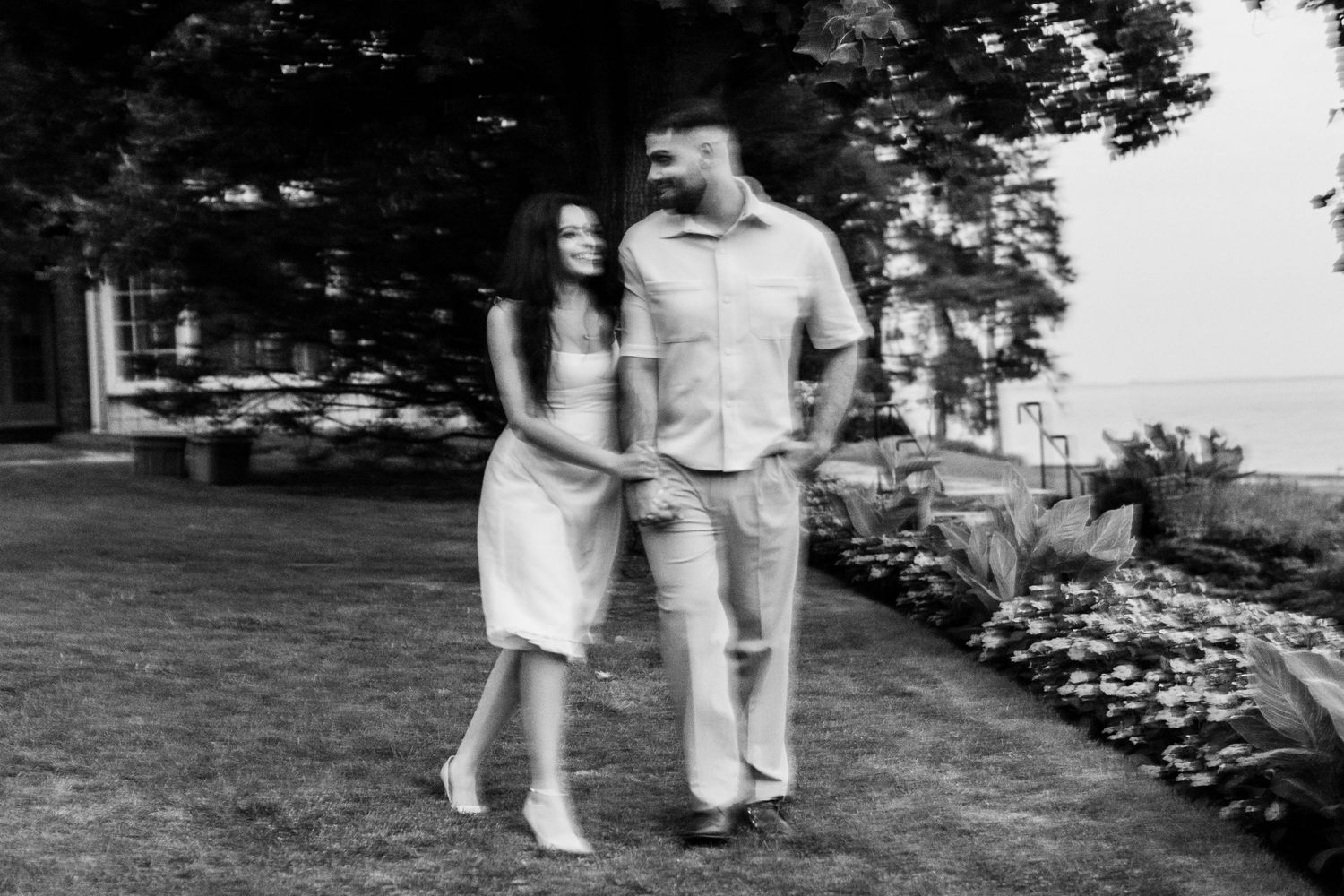 Black and white photo of couple walking together along garden path.