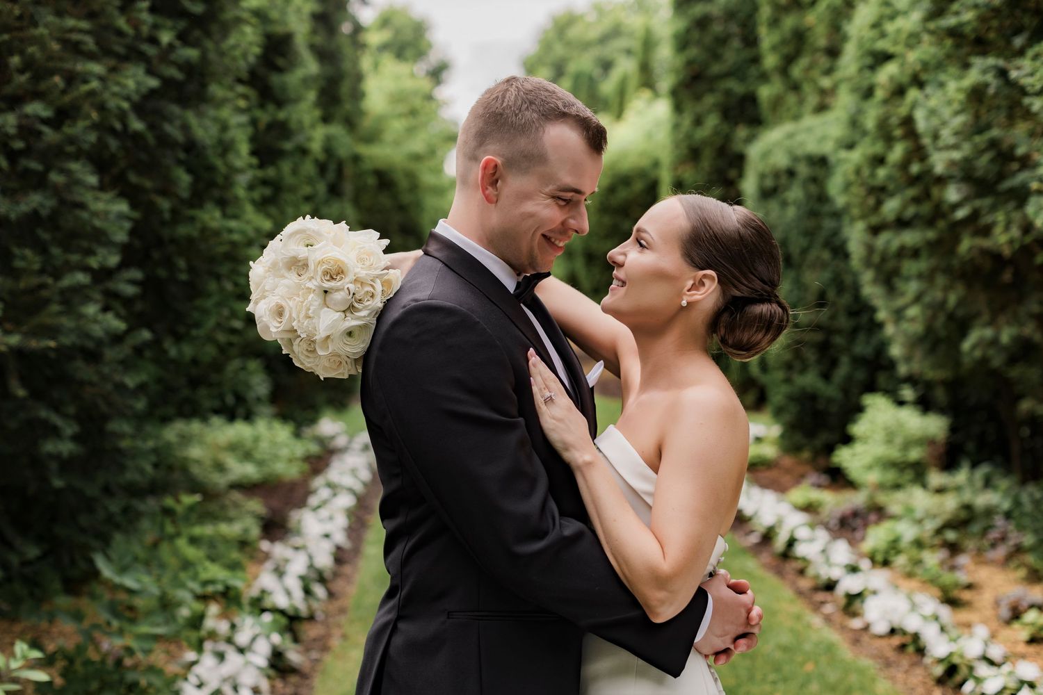 A romantic wedding couple shares tender moments in a lush garden setting.