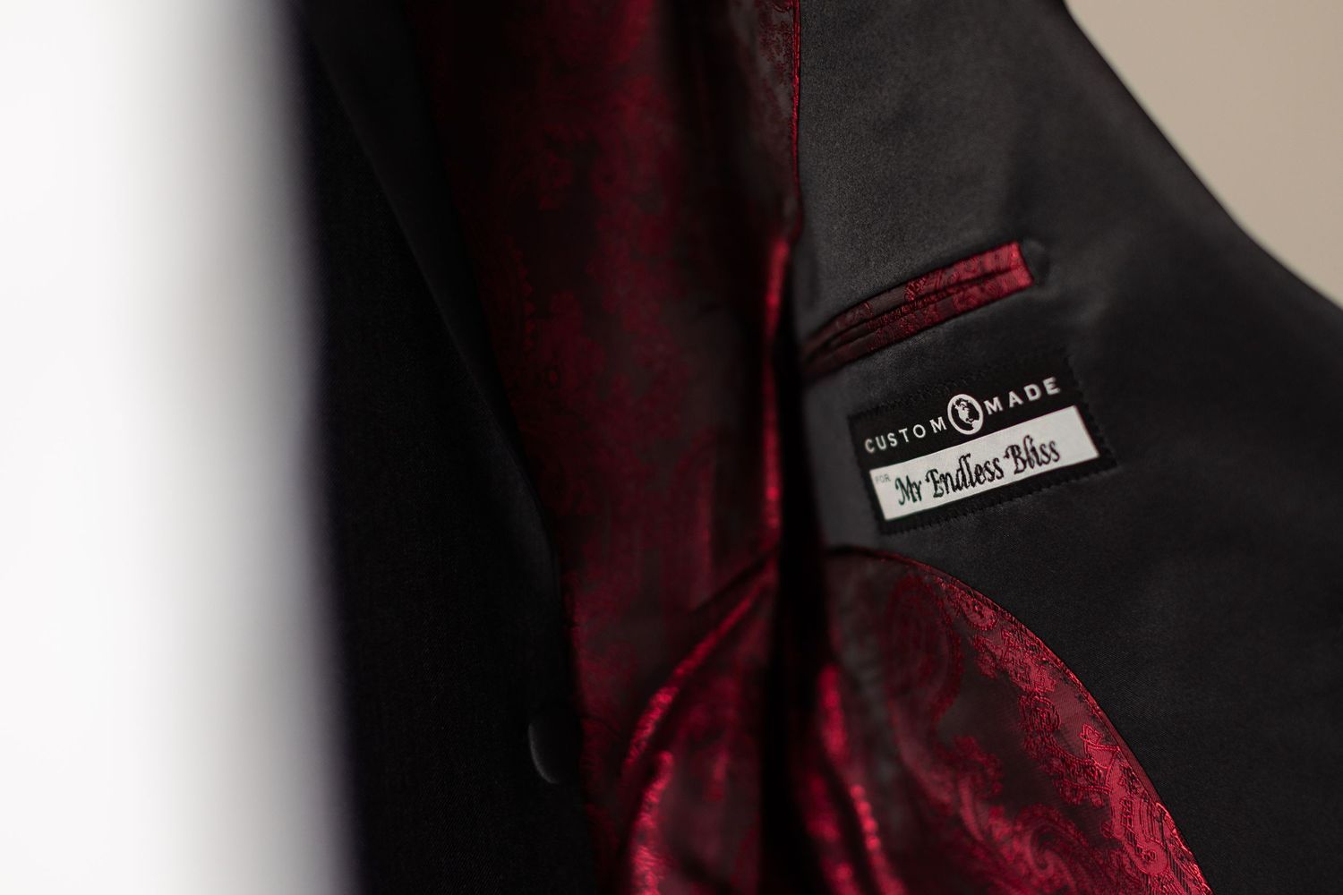 A dark burgundy necktie and formal suit label shown in close-up detail.