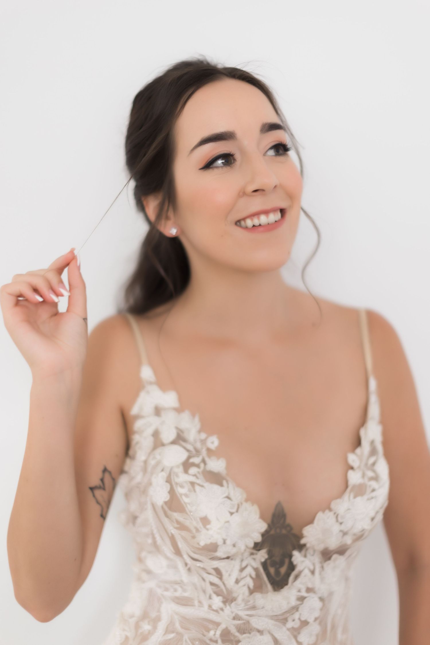Joyful bridal portrait showing intricate lace wedding dress detail against white background.