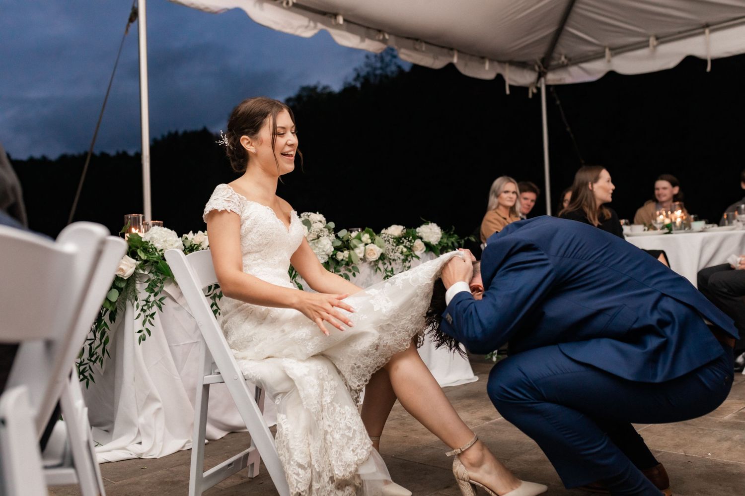 Wedding reception scene with dancing and celebration under an outdoor tent.